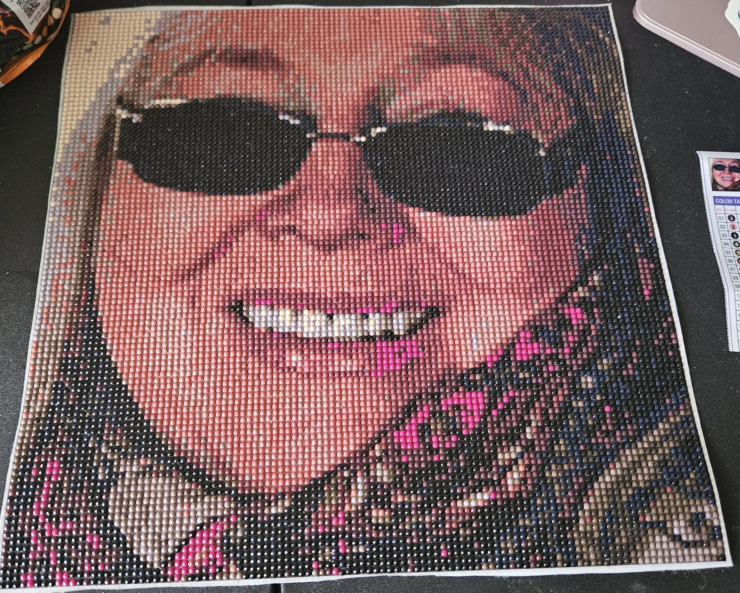 Mosaic artwork of Dwina Murphy-Gibb wearing sunglasses, made from small colorful beads or tiles.