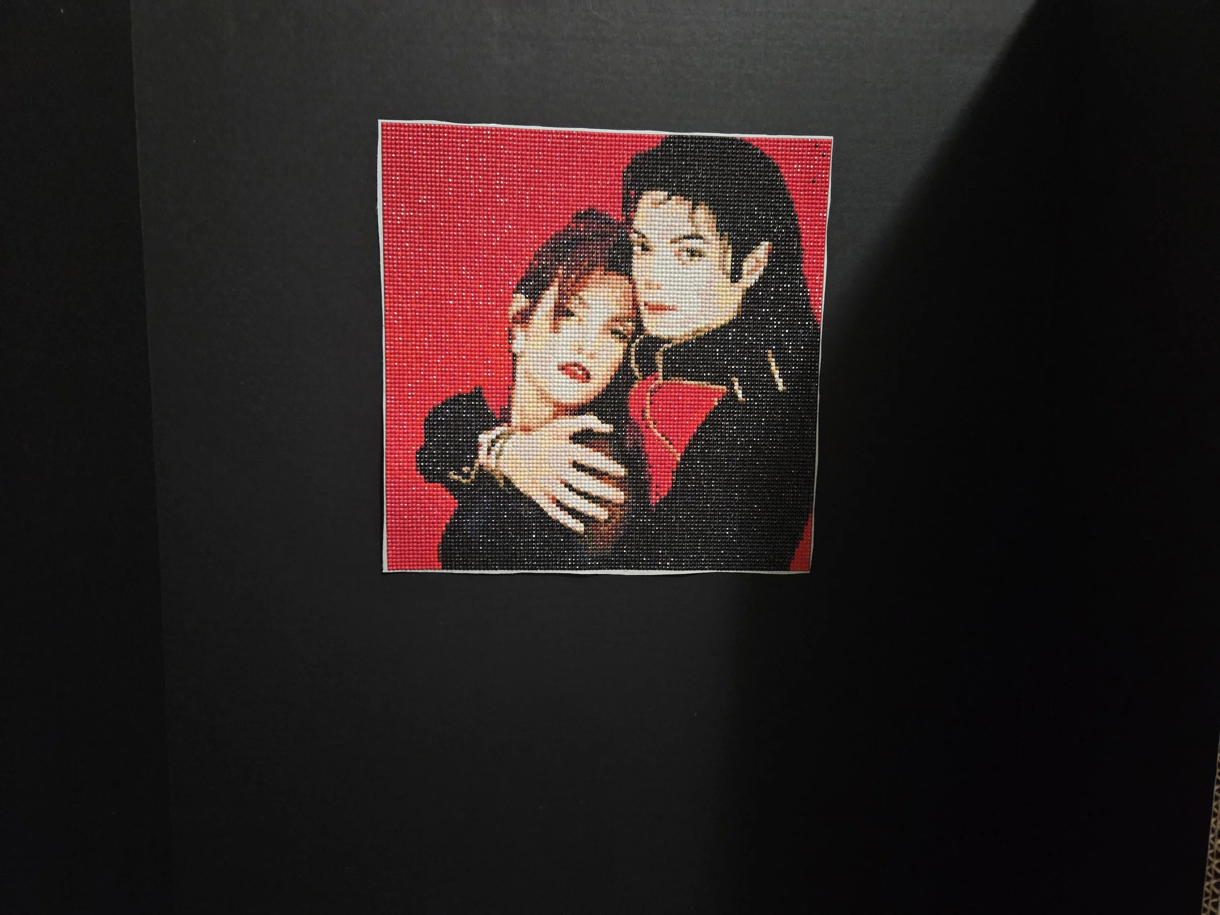 Pixelated portrait of Michael Jackson and Lisa Marie Presley embracing with a red background.