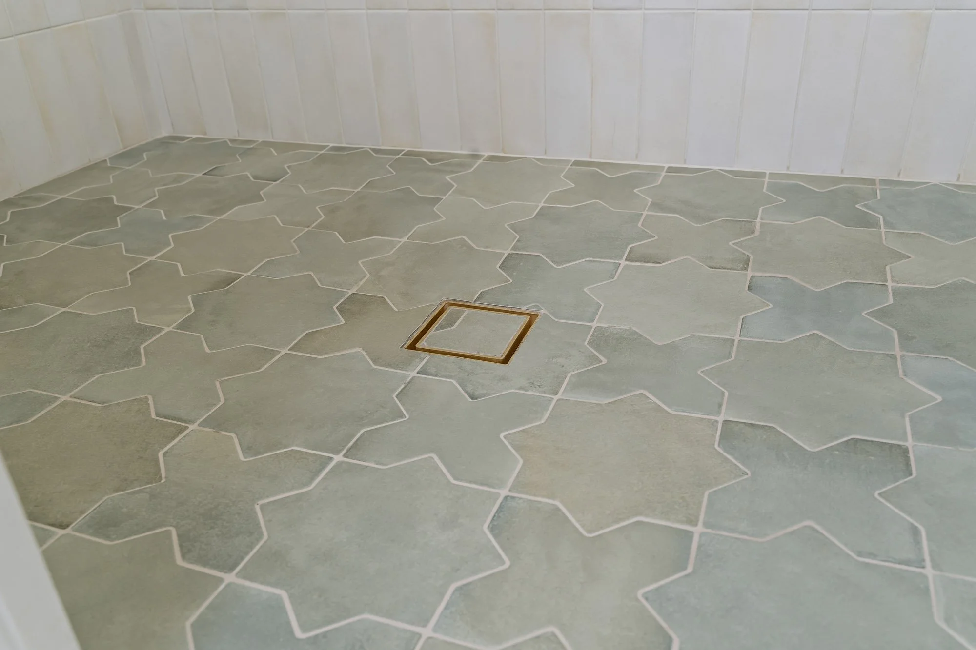 Mission Tile Flooring Cross & Stars porcelain shower floor tile with a brushed brass drain adds character and craftsmanship to this custom Santa Cruz bathroom remodel.