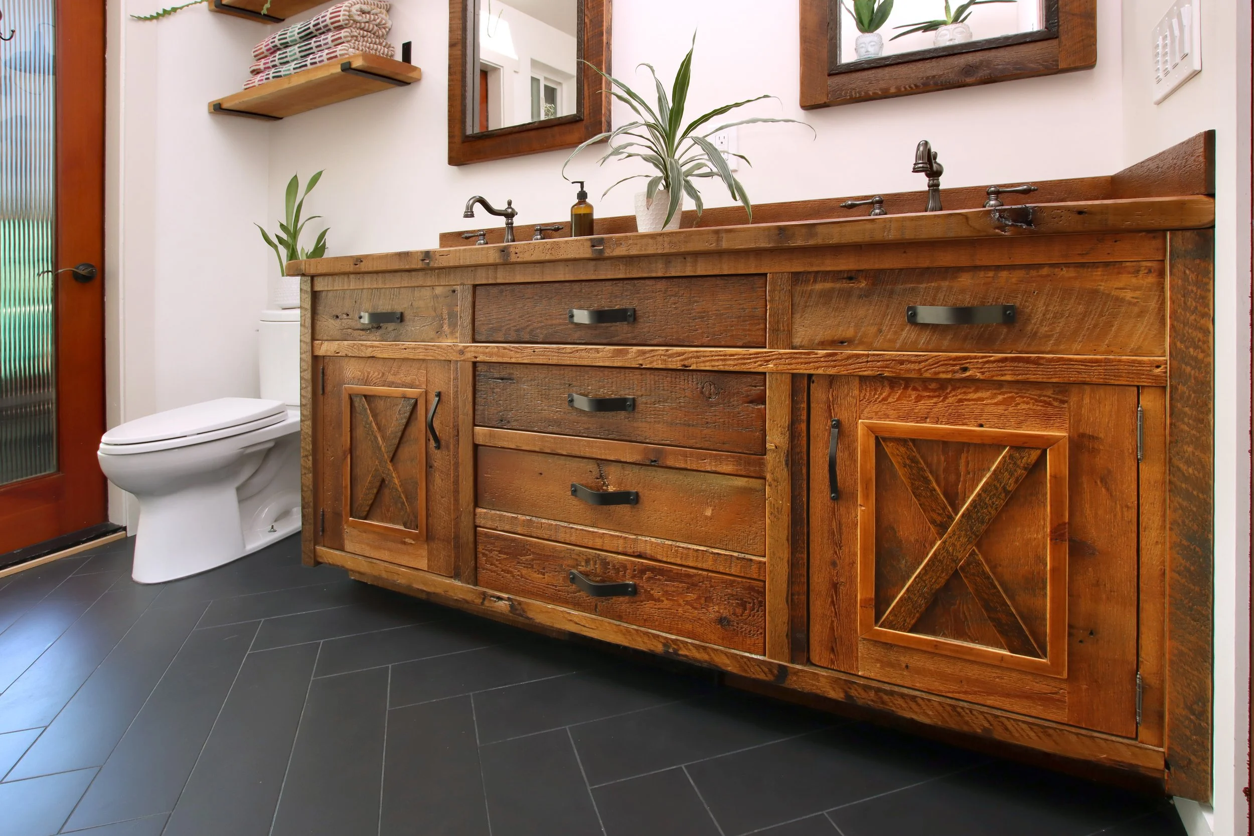 Rustic wood bathroom vanity with farmhouse-style cabinet doors, dark hardware, and natural wood finish in a Santa Cruz County bathroom remodel.