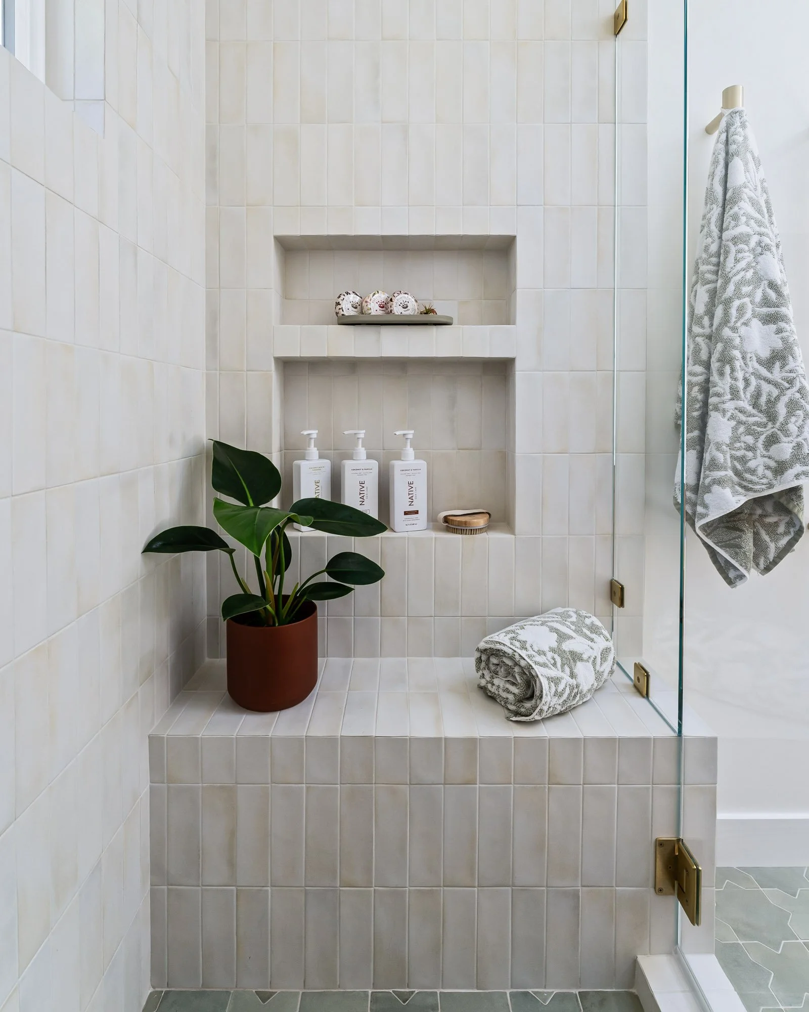 Custom walk-in shower featuring a tiled bench, recessed shelving, and clean, contemporary porcelain tile.