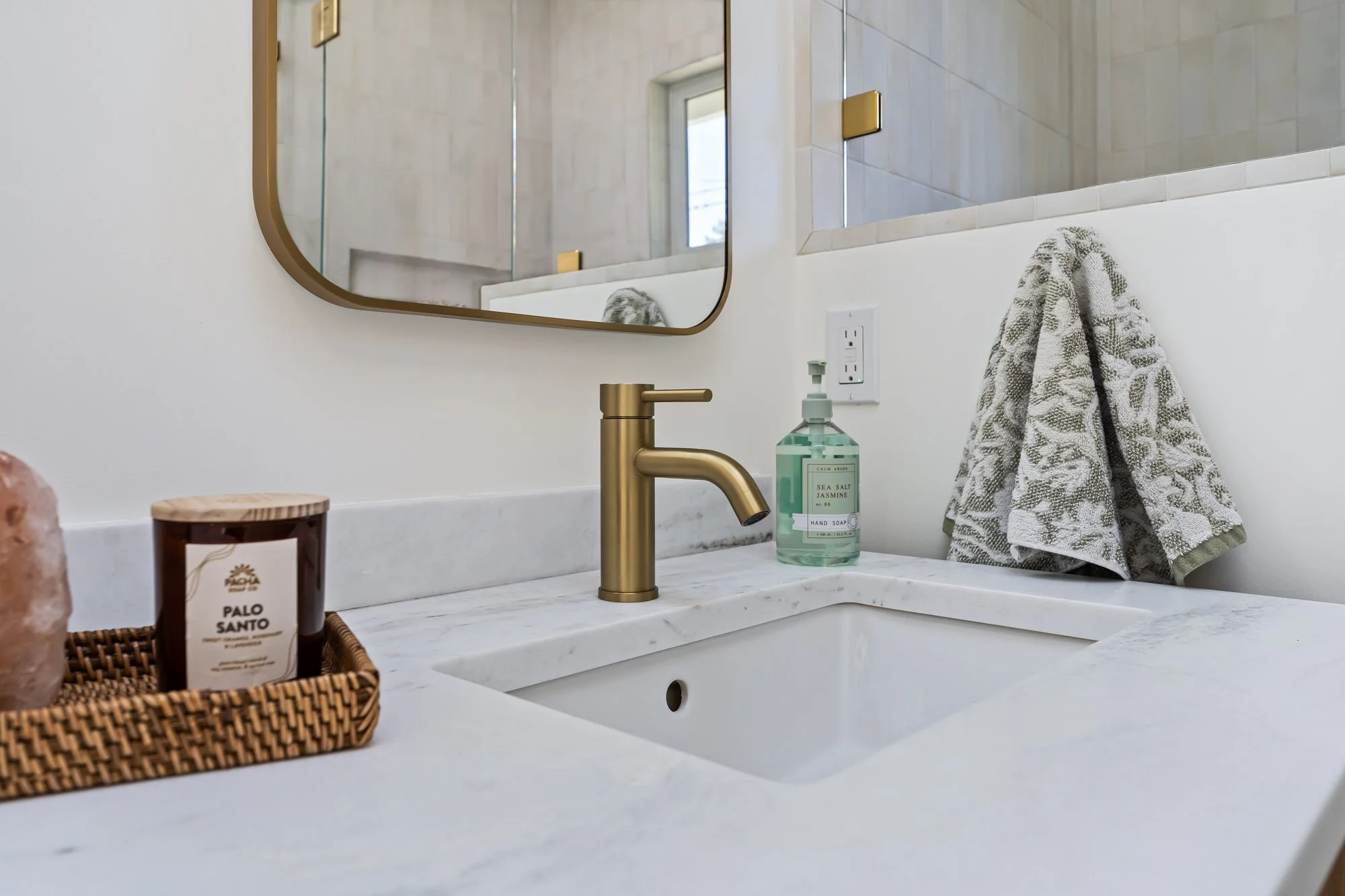 White quartz vanity with an undermount sink, brushed brass faucet, and clean contemporary finishes in a custom Santa Cruz bathroom remodel.