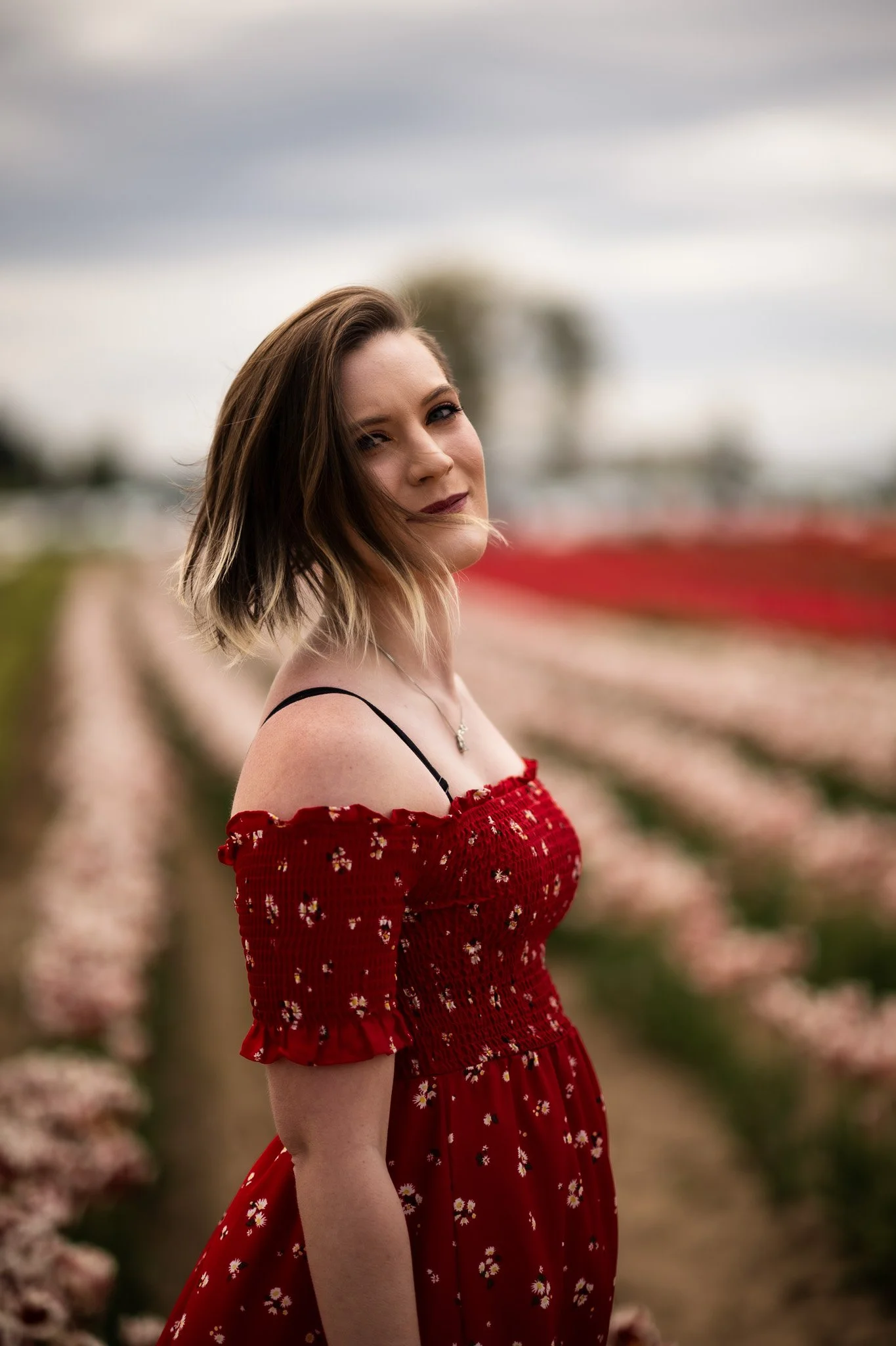 Young Woman with flowing hair in the wind inside a field of tulip flowers