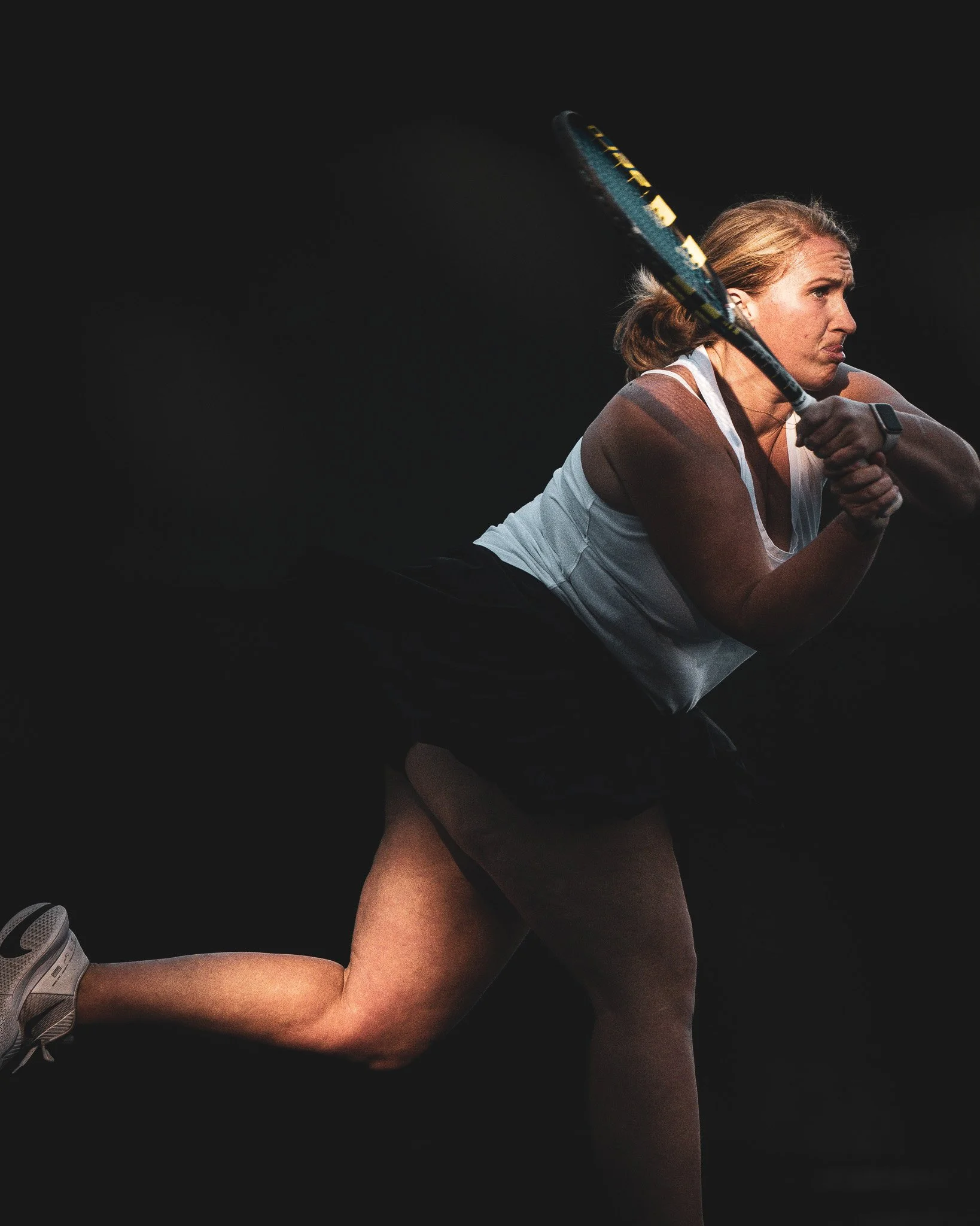 Woman following through on a backhand in a tennis tournament