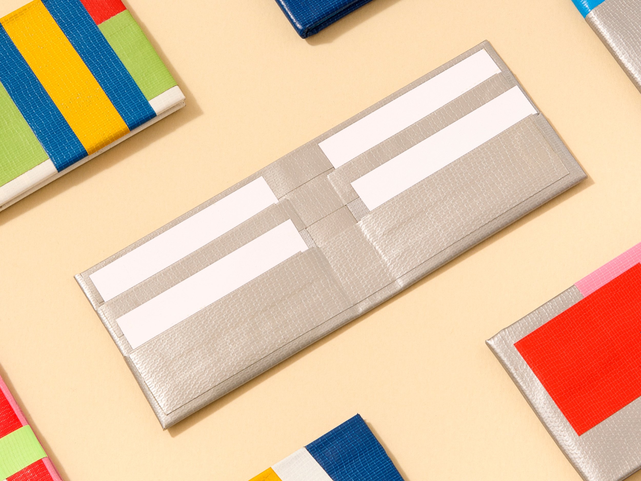 Finished silver Duct Tape Wallet surrounded by bright custom wallets