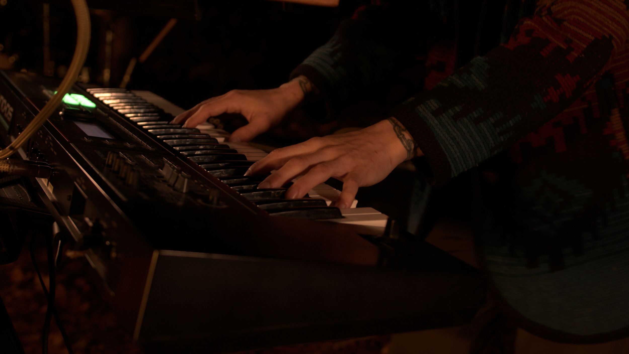 Close-up of a person playing a keyboard or synthesizer, with hands positioned on the keys.