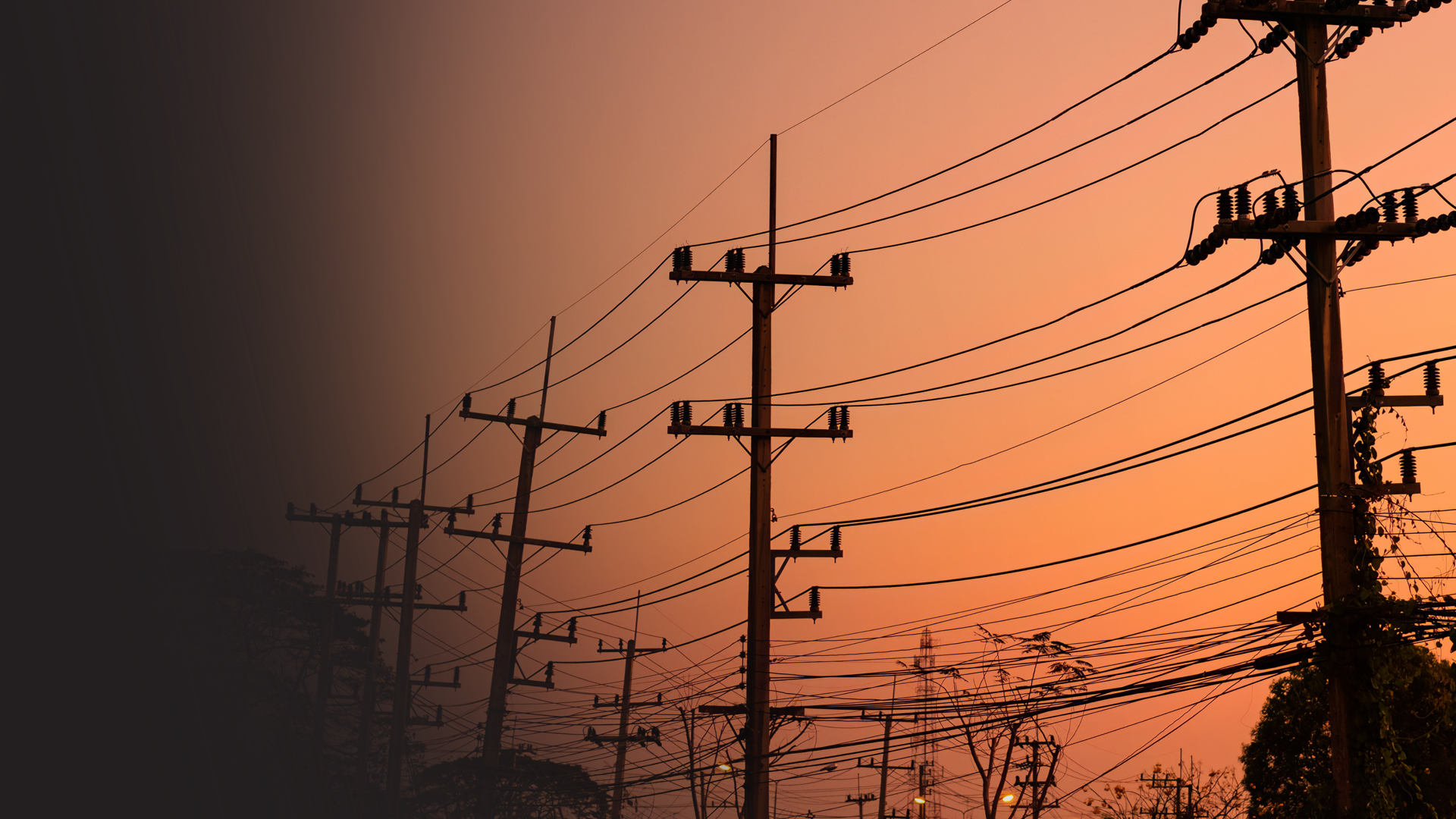 Multiple utility poles with power lines against a colorful sunset sky.