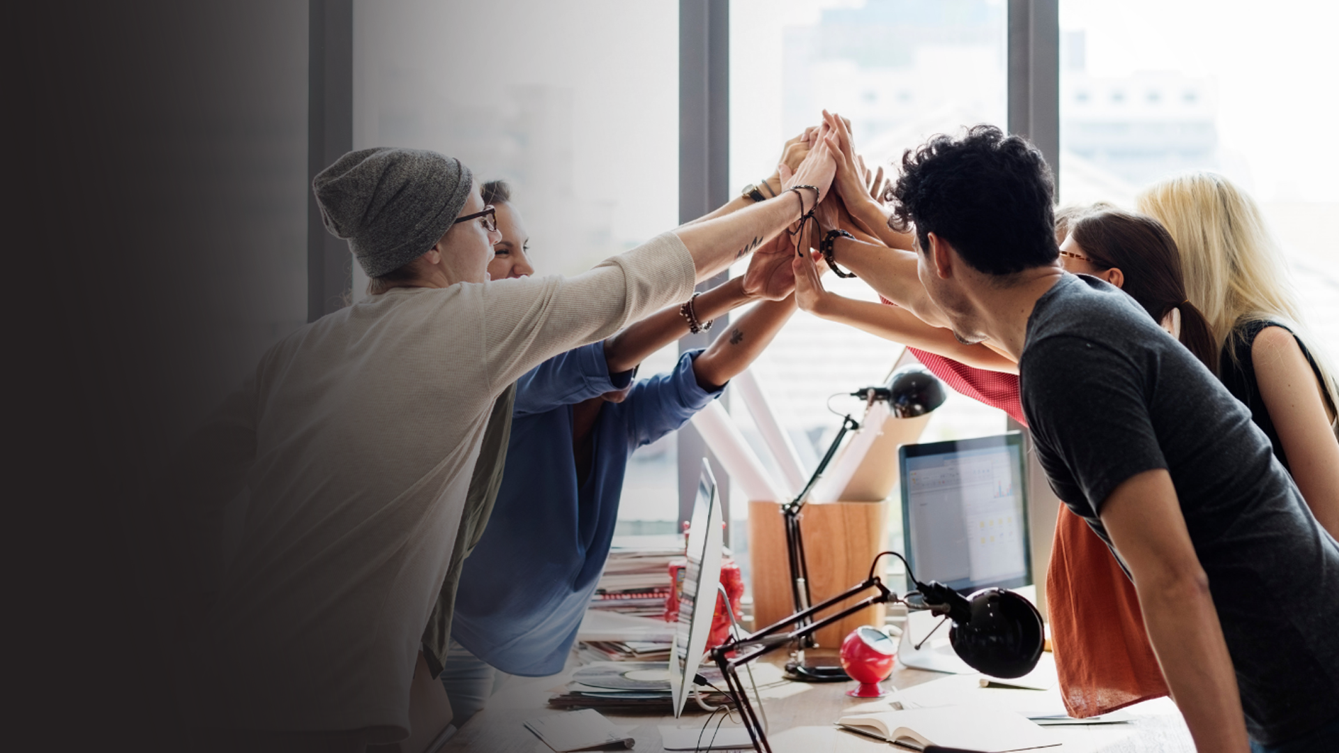 A group of highly engaged and excited employees reaching out for a group high-five