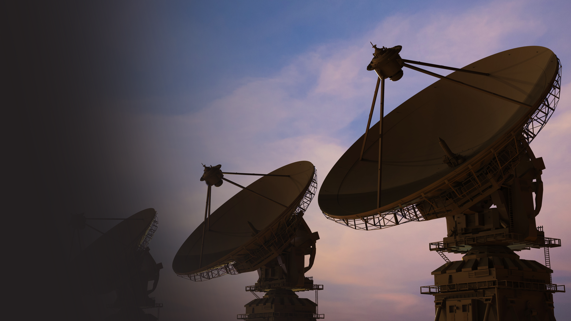 Satellite dishes pointed towards the sky at sunset or dusk.