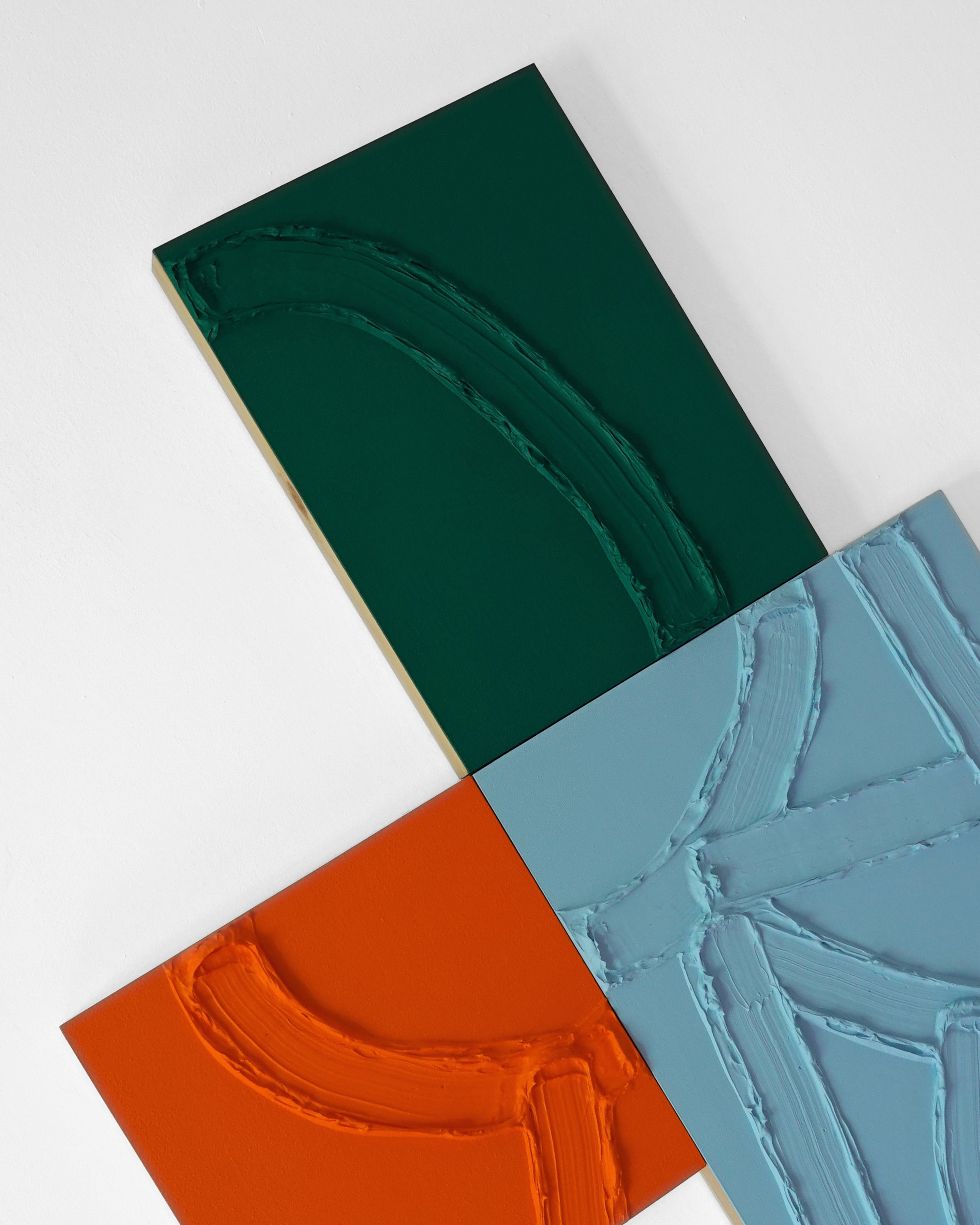 Close-up view of three textured abstract paintings in green, blue, and orange hues, overlapping on a white surface.