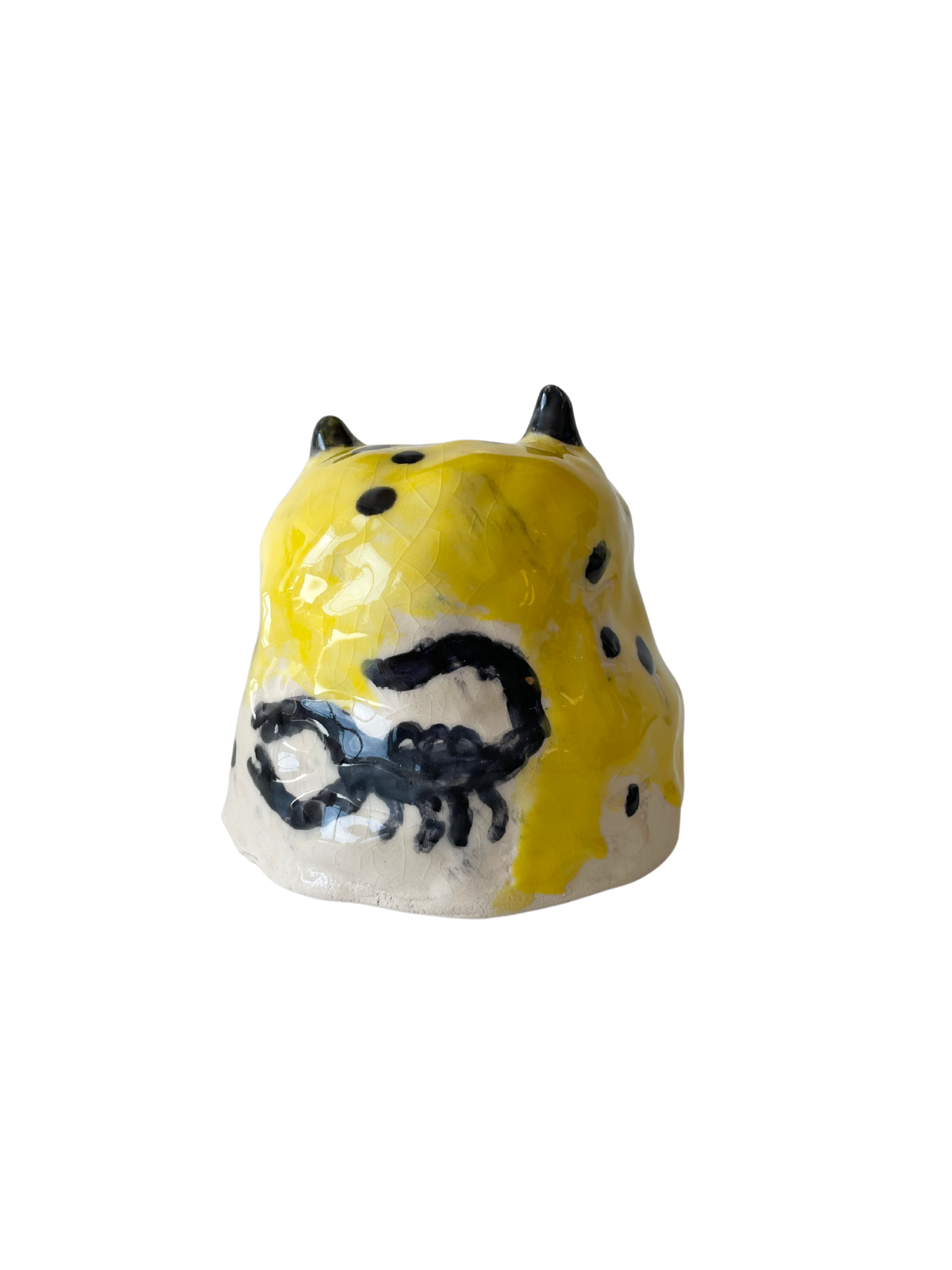Small ceramic sculpture by Abel Kabel. The sculpture is yellow with a scorpion painted on the side.