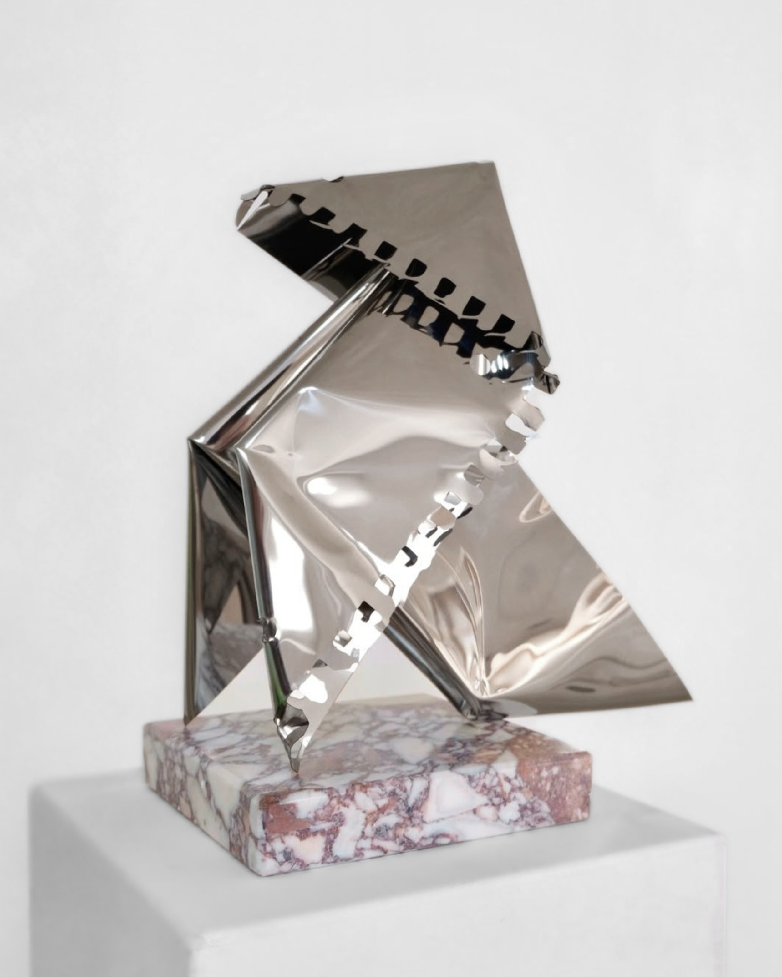 A metallic sculpture of an umbrella on a pink marble base, displayed against a white background.