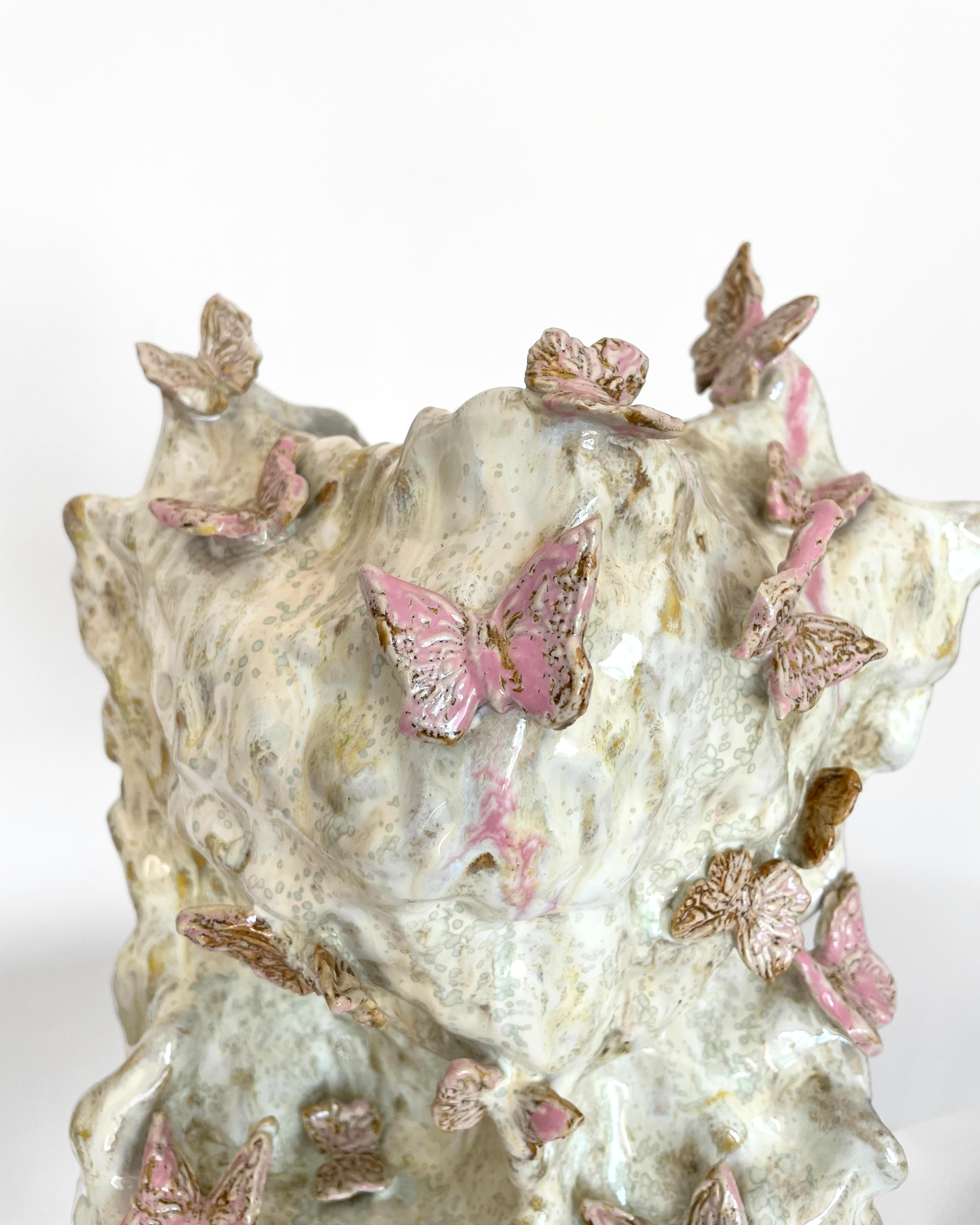 A ceramic vase decorated with pink and brown butterflies, featuring a textured and glossy surface.