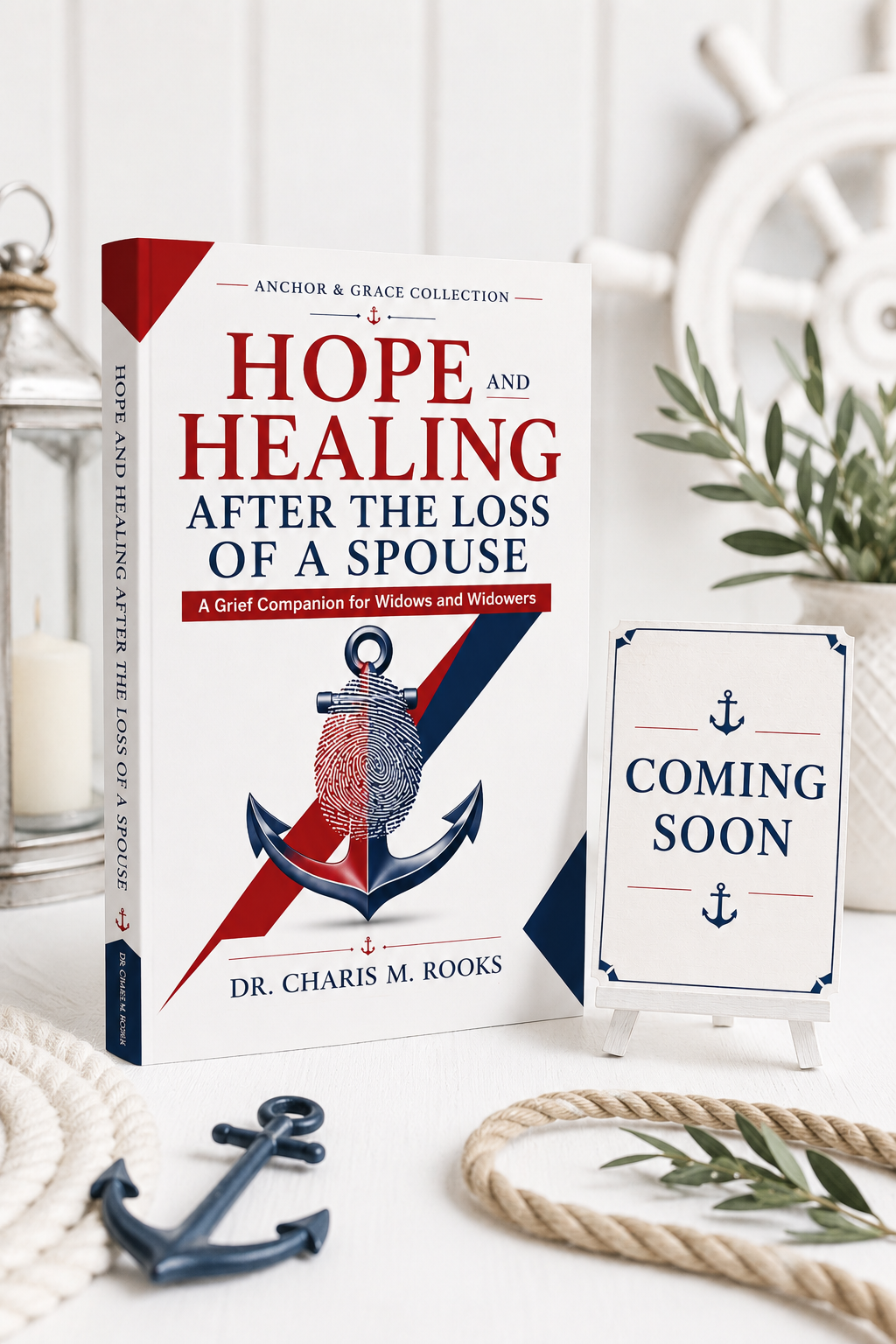 A book titled "Hope and Healing After the Loss of a Spouse" by Dr. Charis M. Rooks, a sign that says "Coming Soon," nautical decorative items including an anchor, a rope, and an anchor illustration on the book, and some greenery in the background.