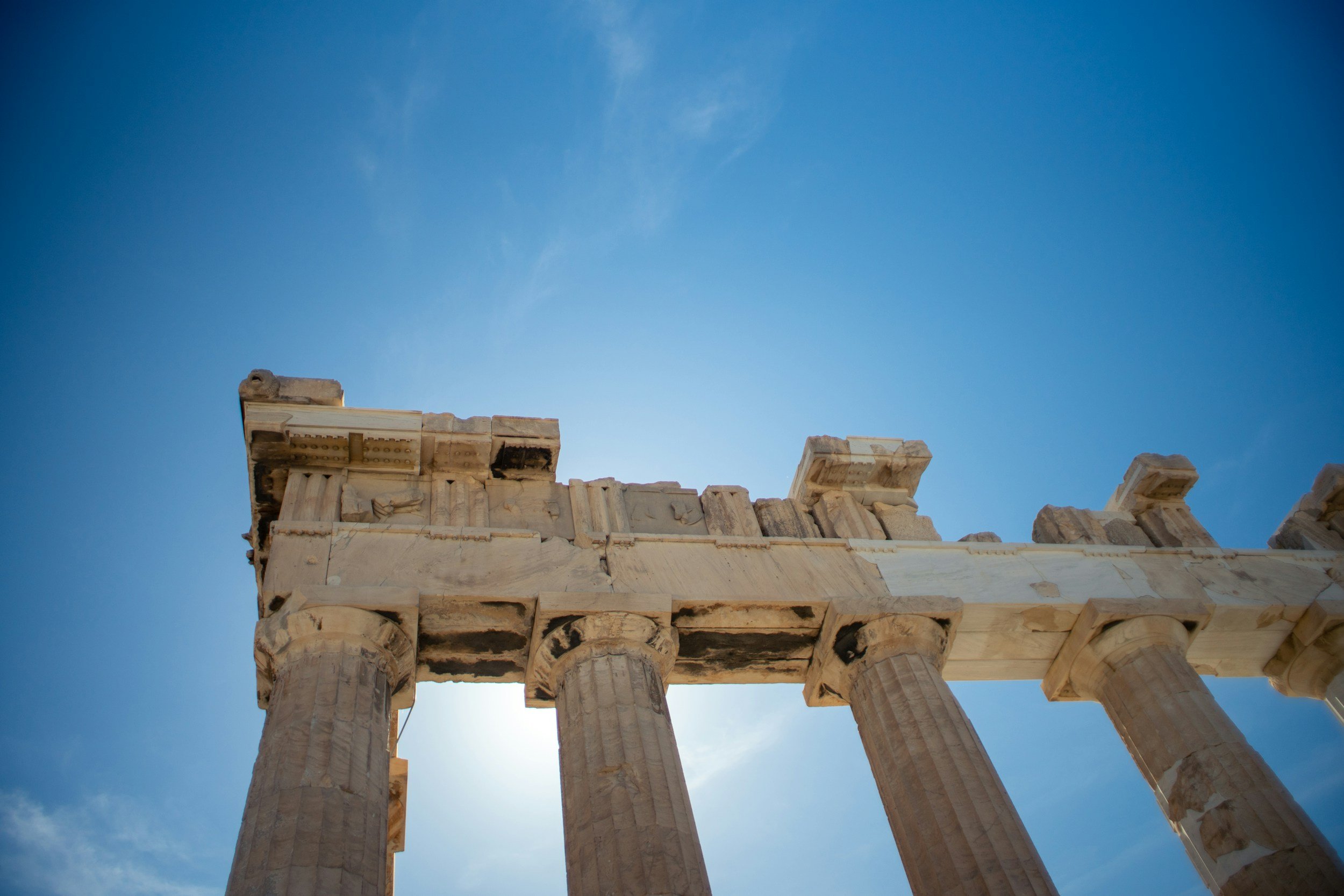 Ancient Greek ruins with tall stone columns against a clear blue sky.
