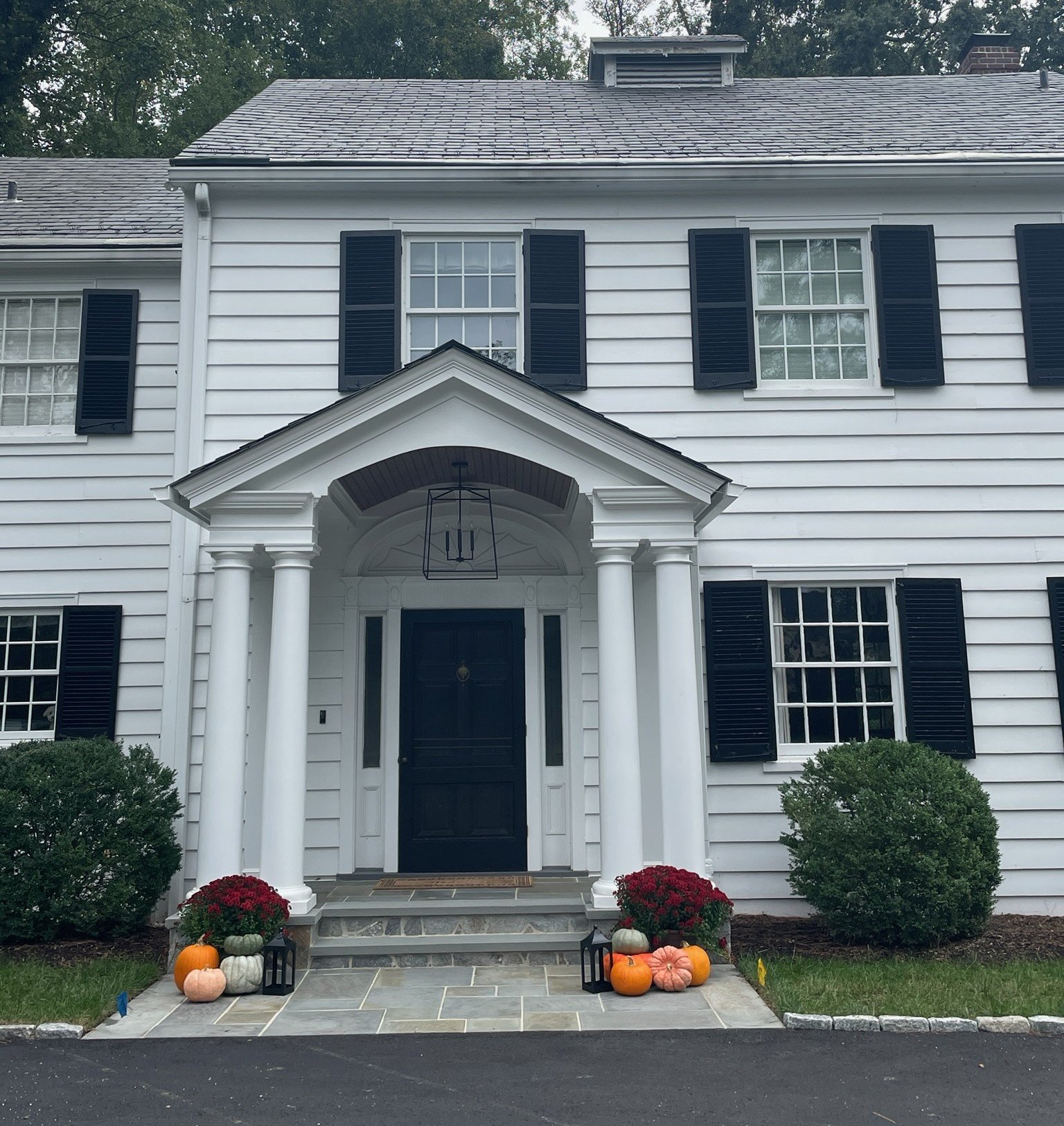 Completed porch addition at a historic Colonial Revival home in Henrico, Virginia, featuring paired white columns, an arched ceiling, a hanging lantern, and stone steps.