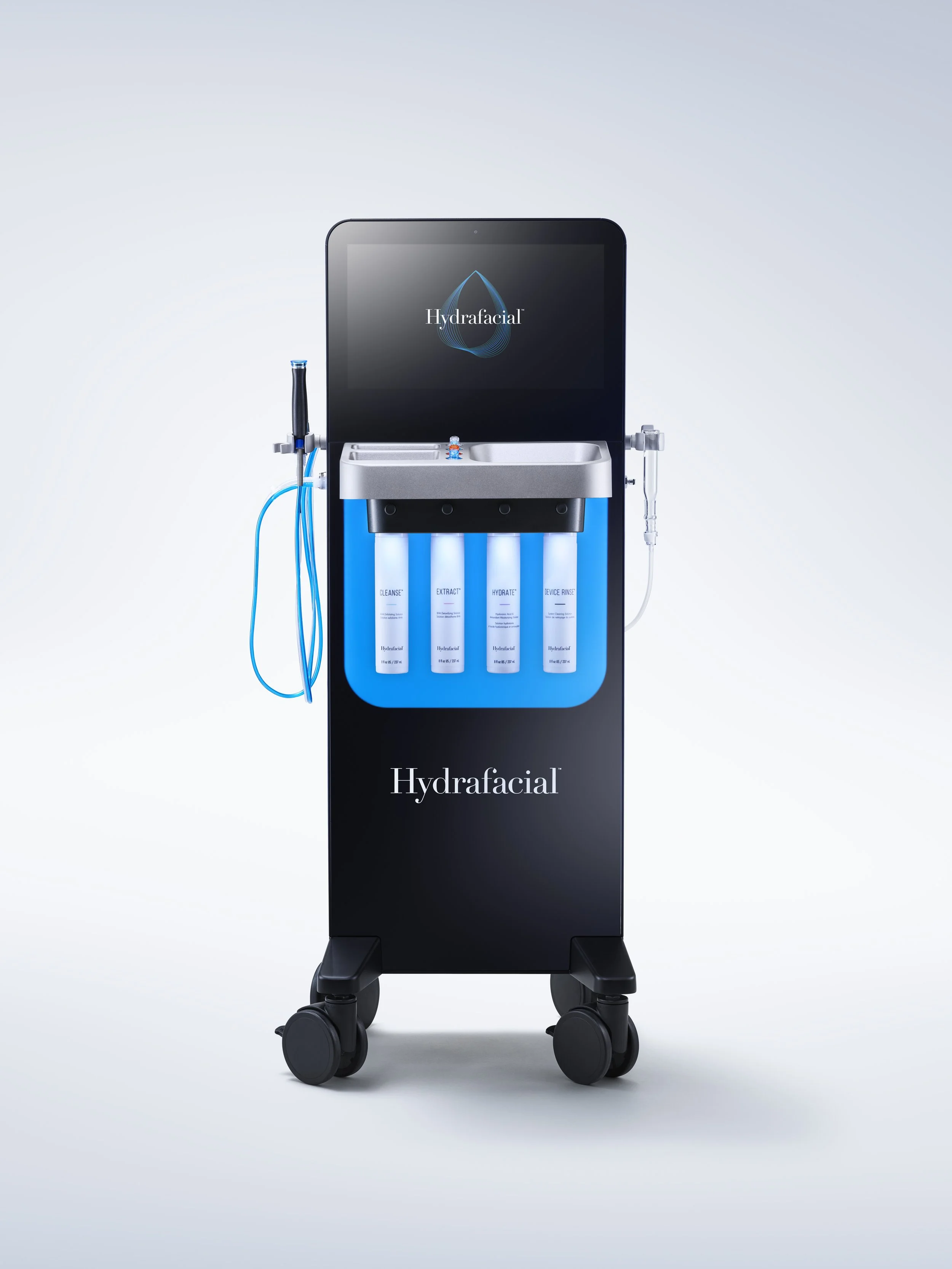 A Hydrafacial machine with a digital screen, four labeled bottles, and connected tubes on a mobile stand.