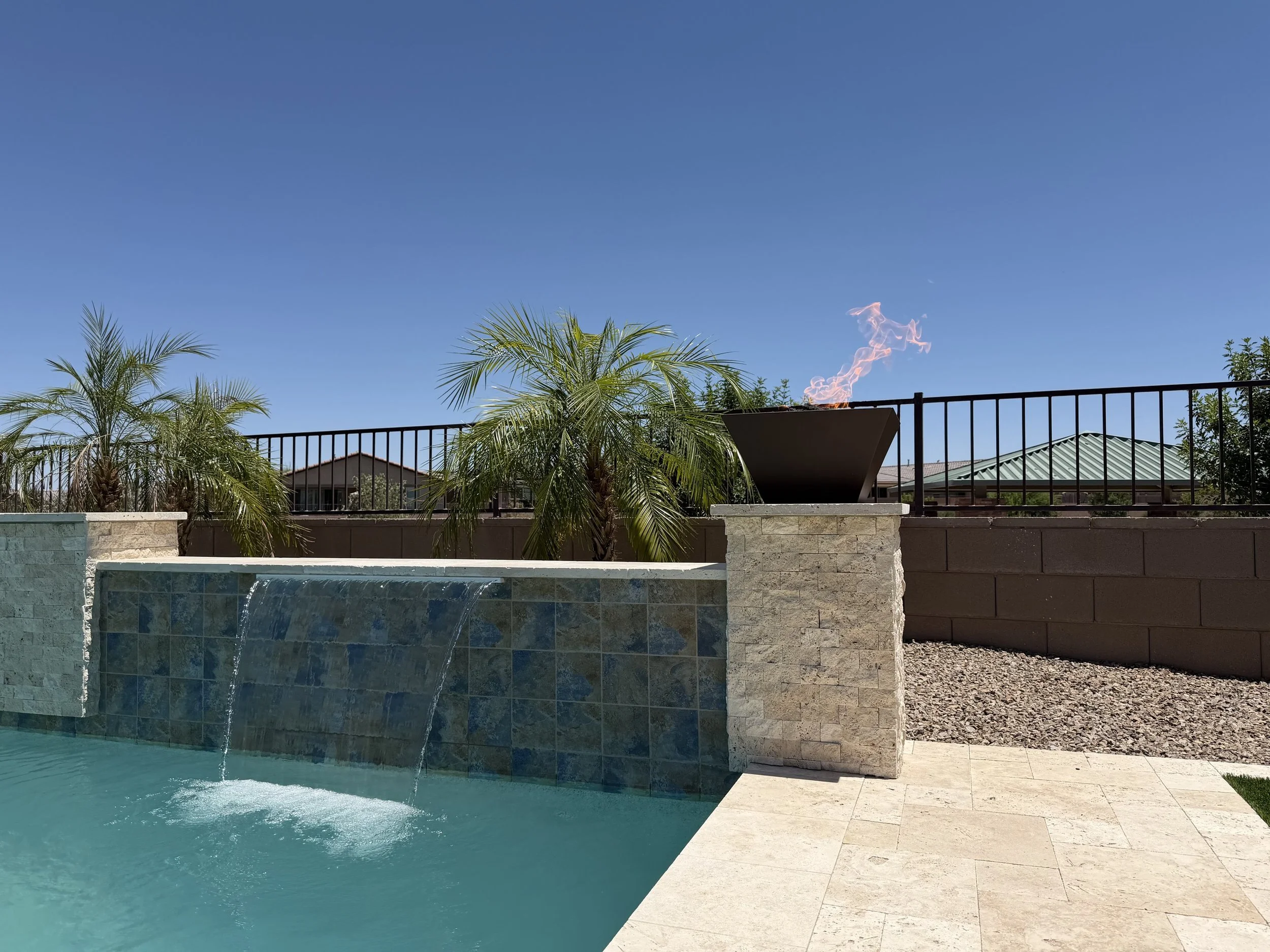Custom pool with fire and water features including a fire bowl and sheer-descent waterfall, by Meraki Pools AZ in Tucson, Arizona.