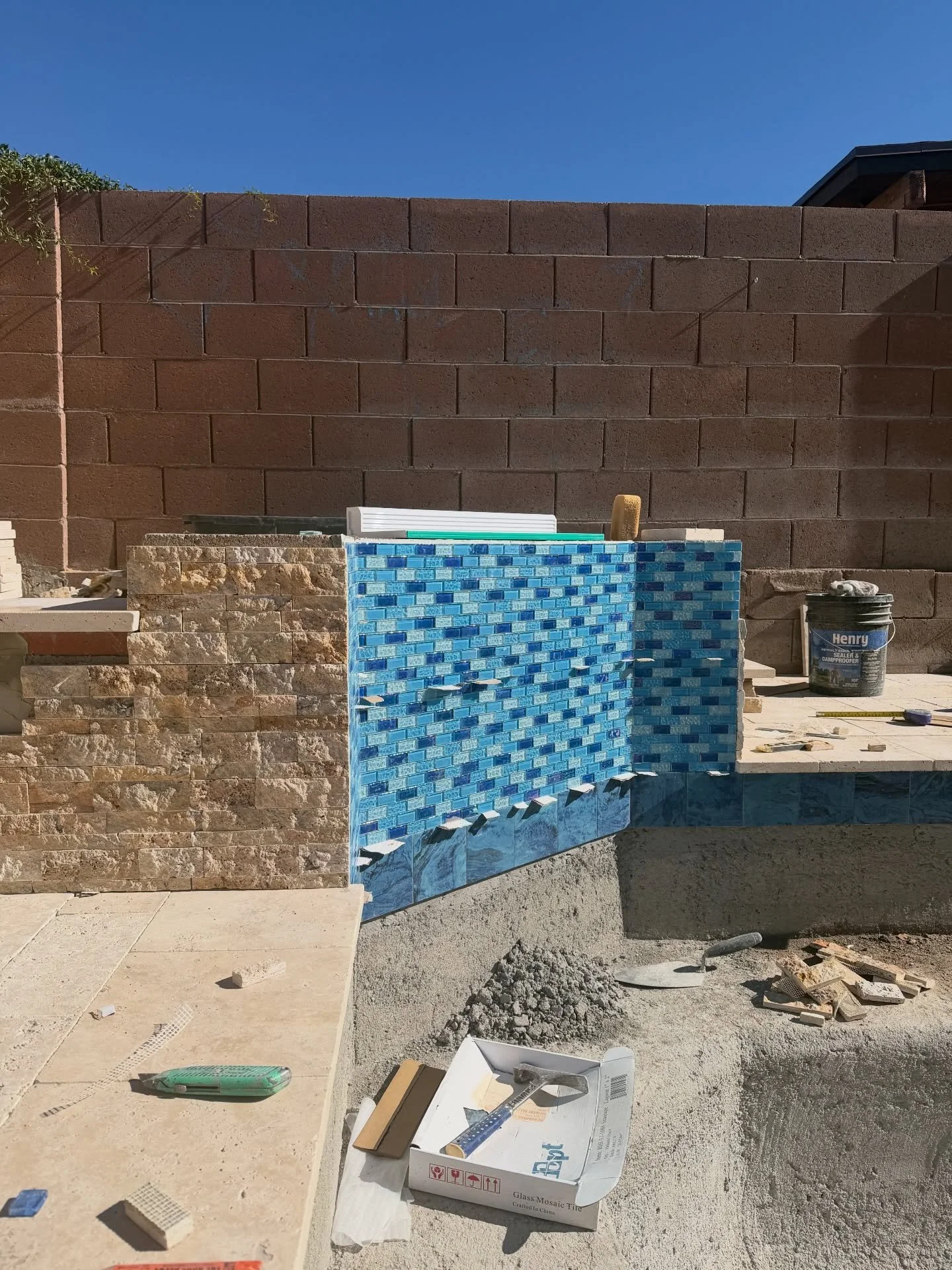 Glass tile upgrade in progress 💎 This water feature is coming together beautifully. Mixing materials like stacked stone, travertine, and bold blue glass for contrast that really stands out. A sheer descent up top will bring that clean, elegant flow 