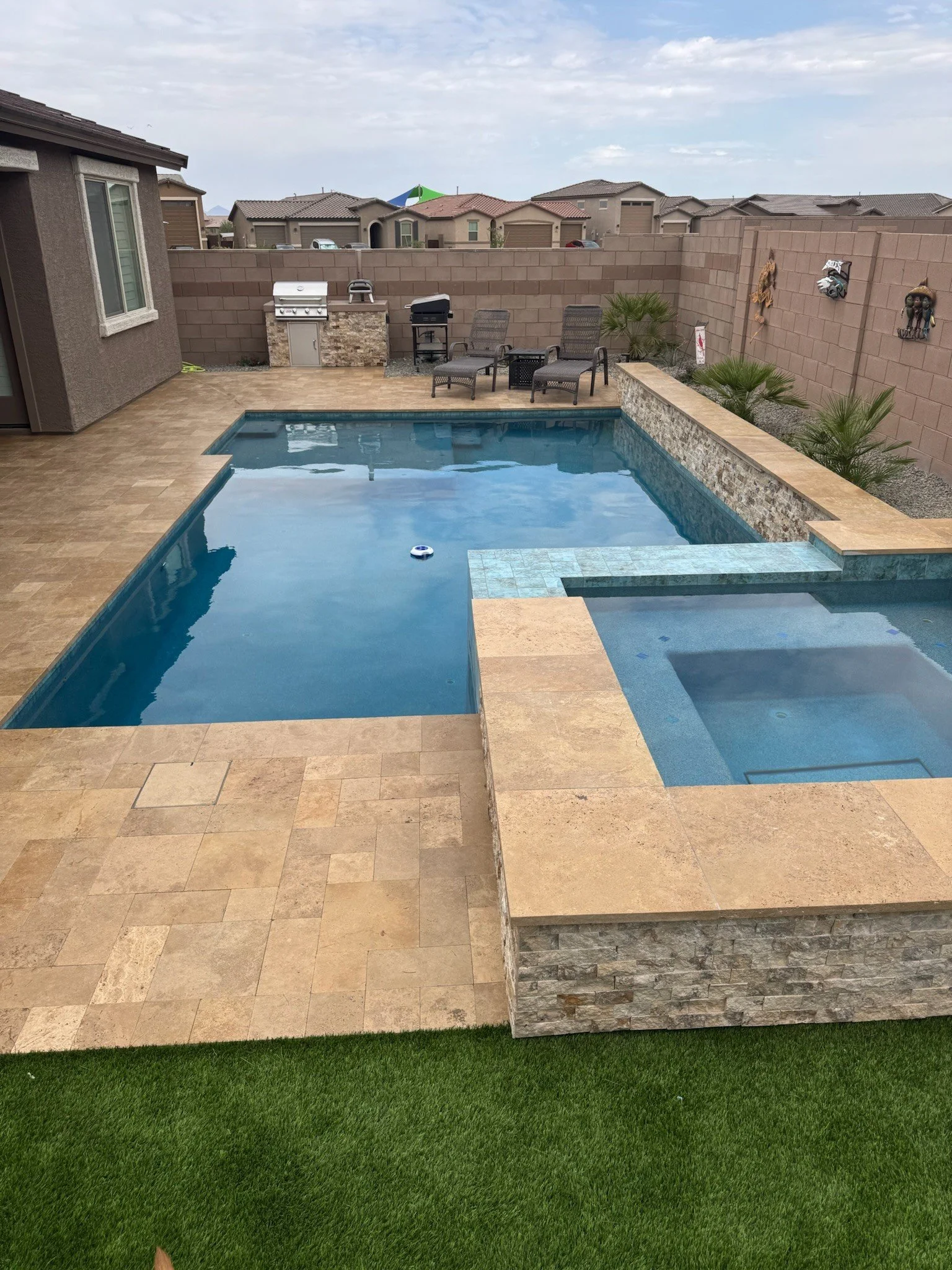Clean geometric swimming pool with a wide travertine surround and seating, custom-built by Meraki Pools AZ in Tucson, Arizona.