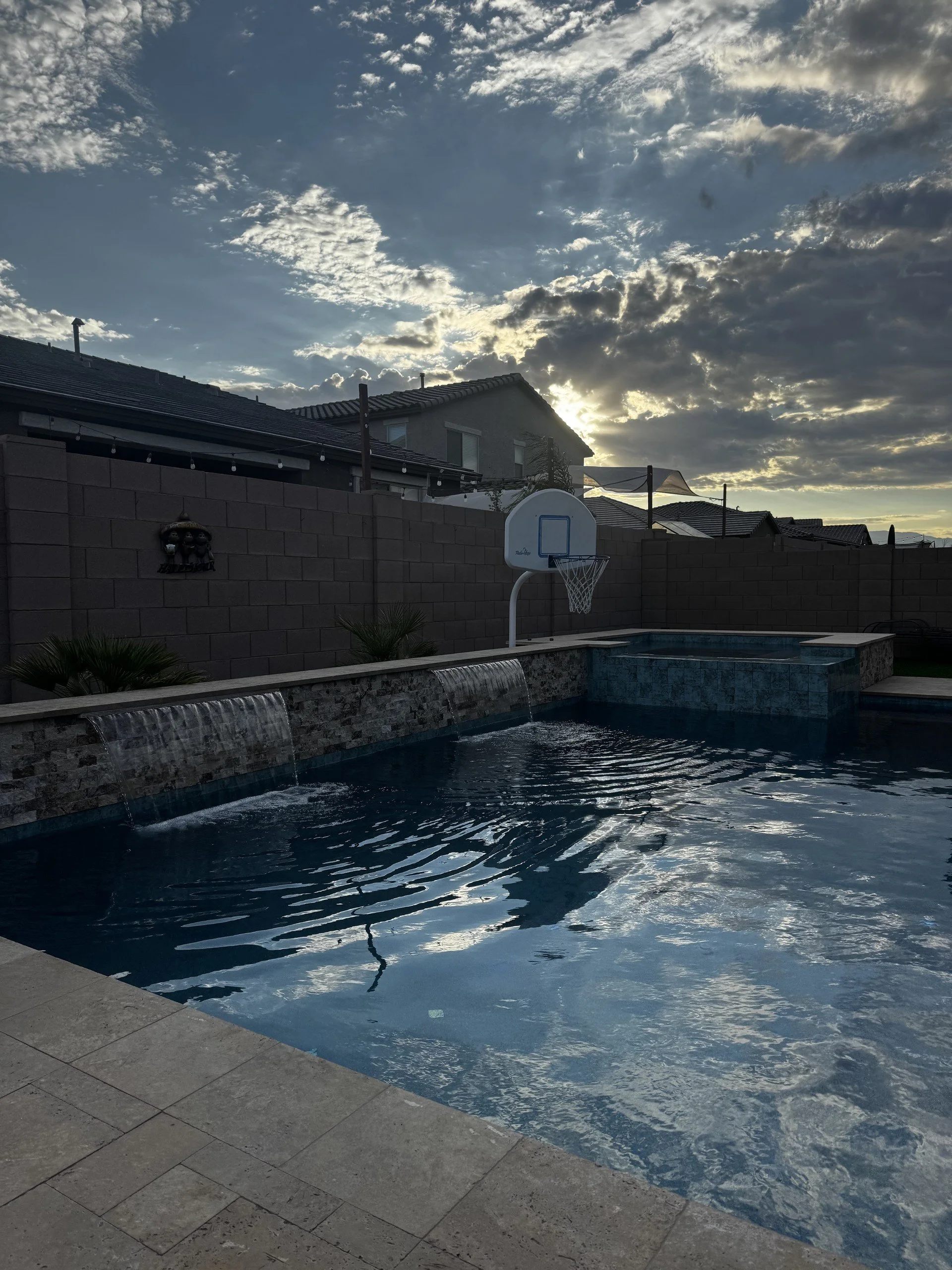 Custom swimming pool with travertine decking and a shaded ramada, built by Meraki Pools AZ in Tucson, Arizona.