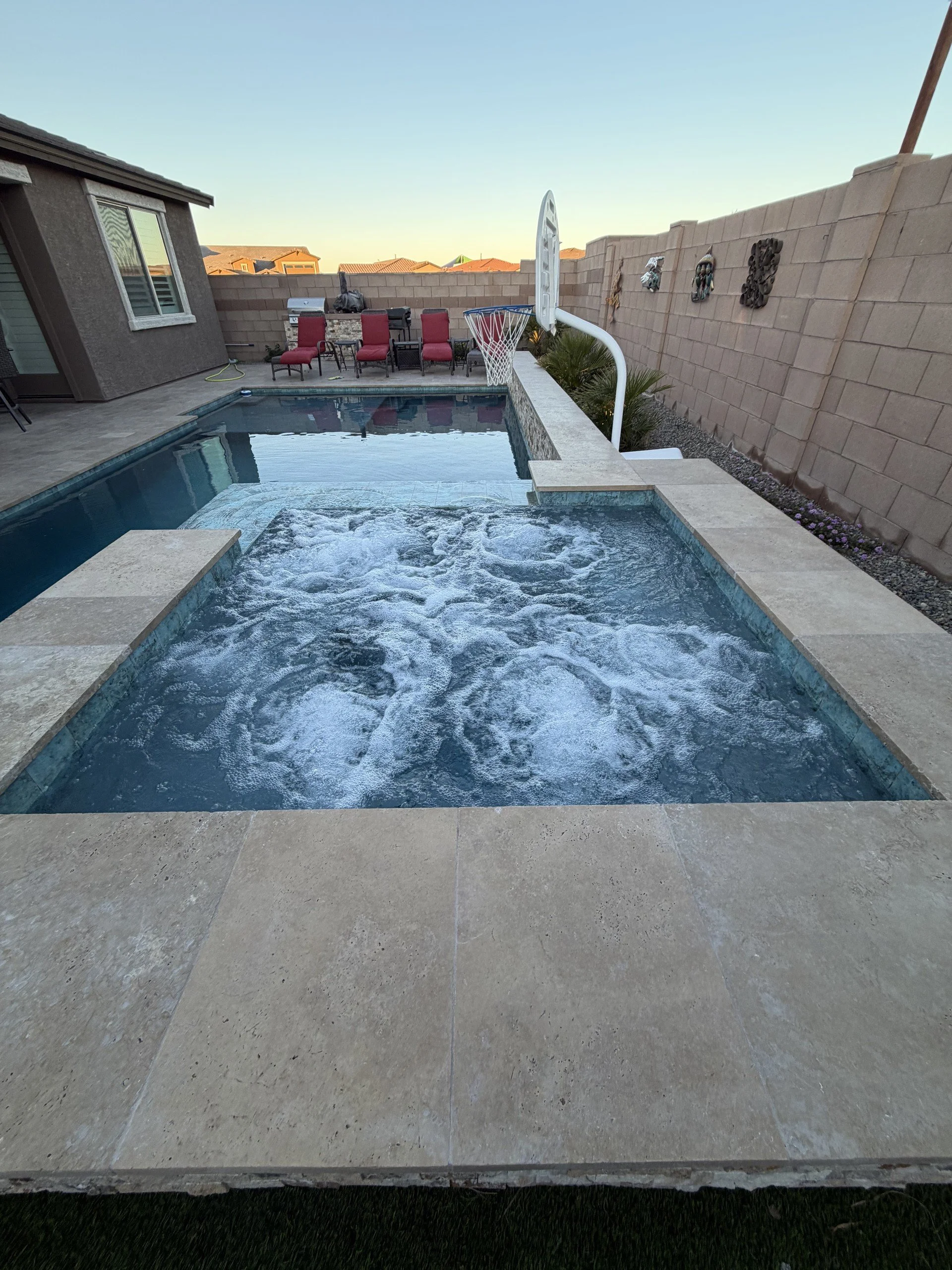 Custom pool and raised spa with a built-in BBQ and outdoor living space by Meraki Pools AZ in Tucson, Arizona.