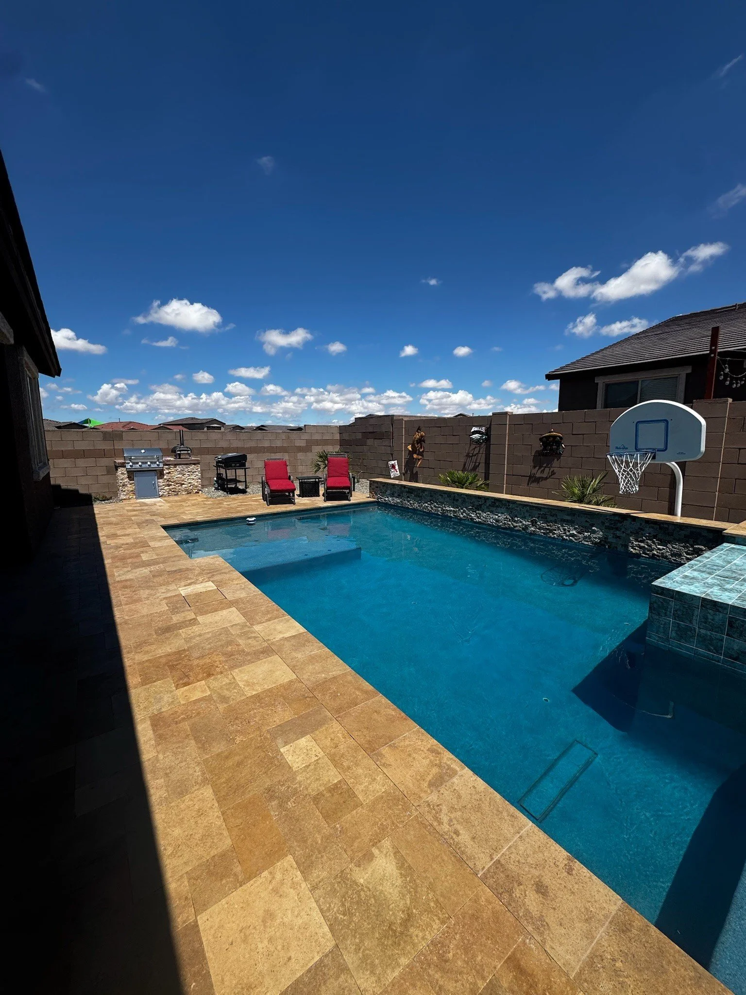 Custom pool with a raised spa at dusk and travertine decking by Meraki Pools AZ in Tucson, Arizona.