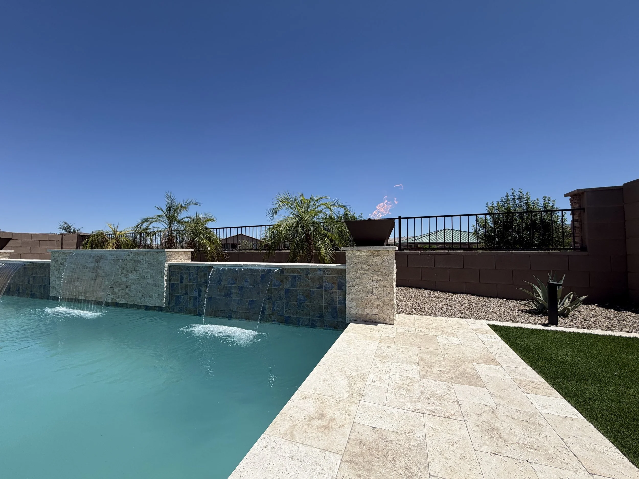 Custom modern pool with bubbler jets, a sheer-descent water feature, and turf landscaping by Meraki Pools AZ in Tucson, Arizona.