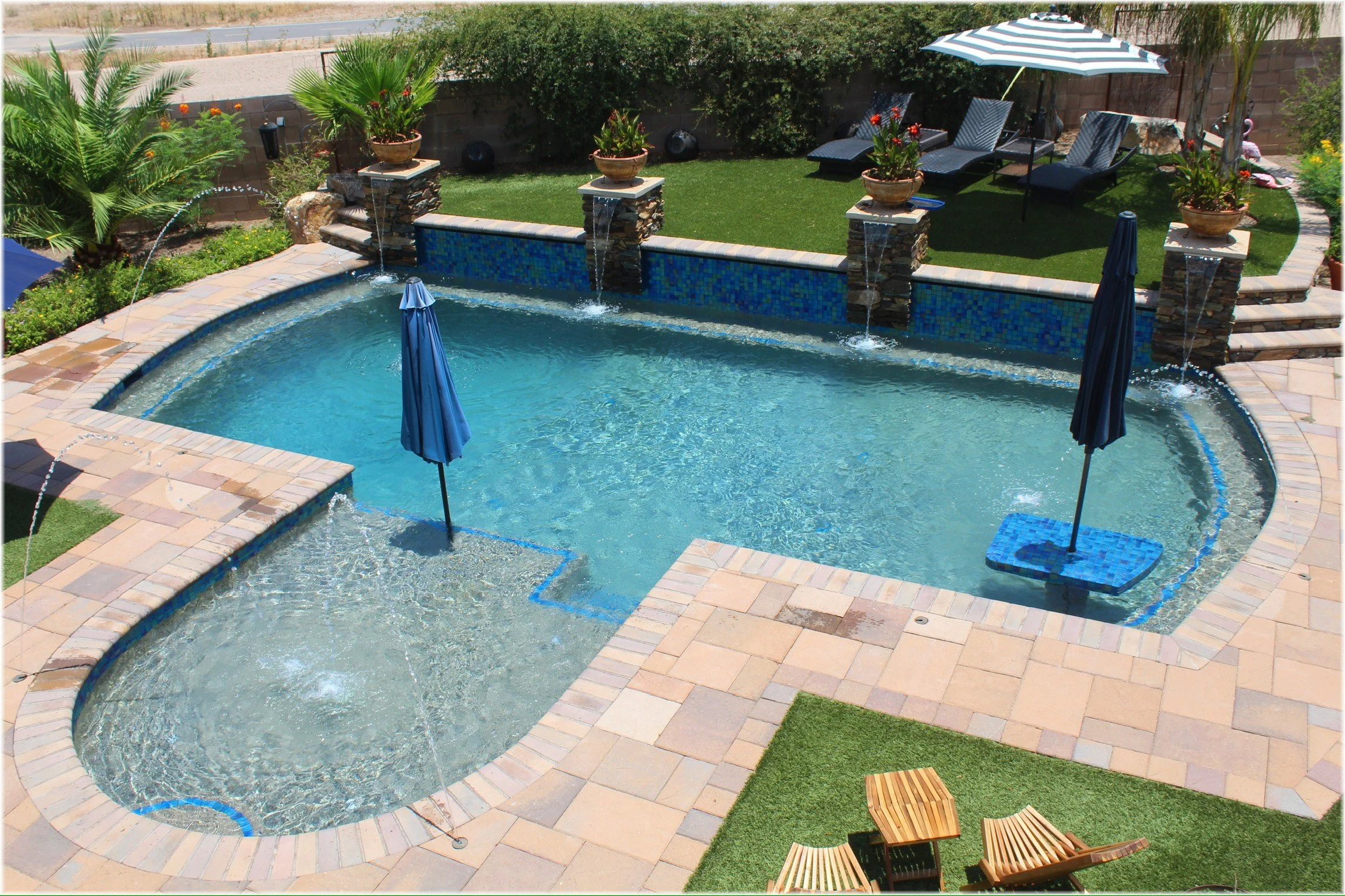 Freeform backyard pool with glass tile and water features, custom-built by Meraki Pools AZ in Tucson, Arizona.