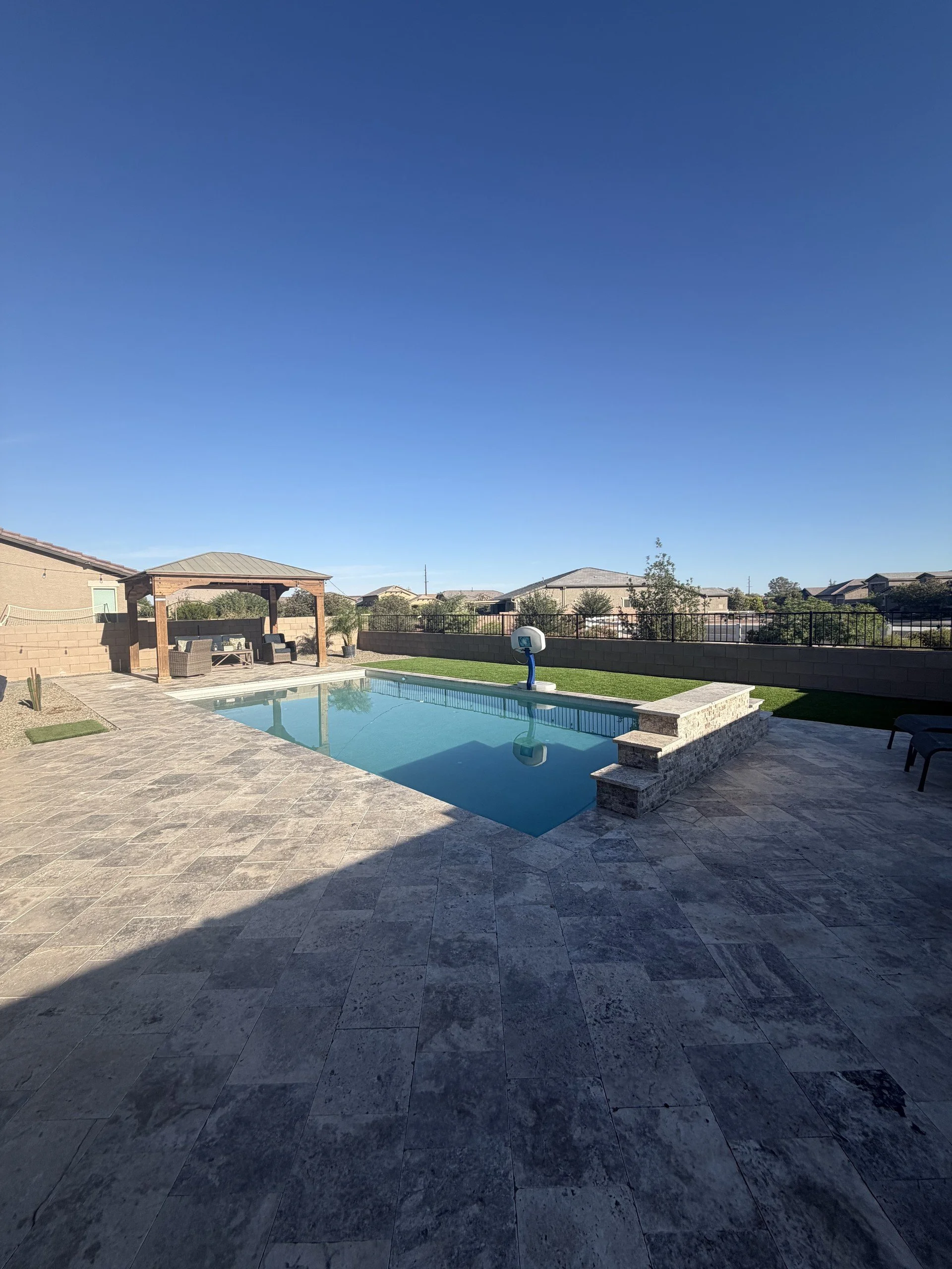 Modern geometric pool with a raised spa and travertine deck, custom-built by Meraki Pools AZ in Tucson, Arizona.