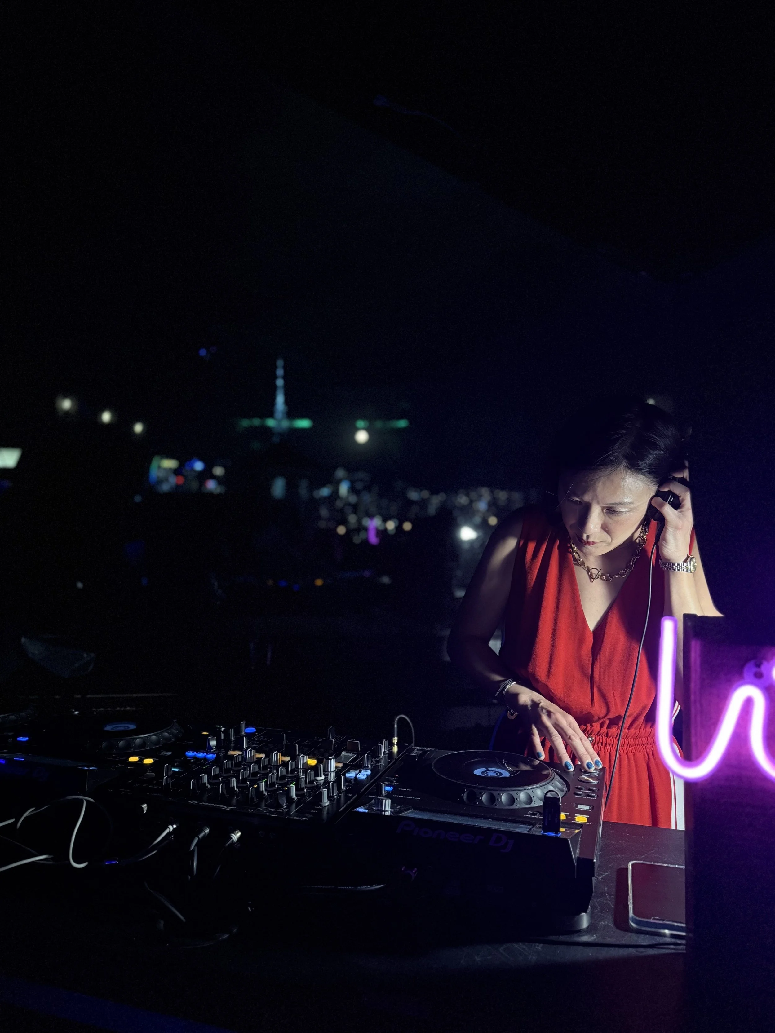 A DJ's hand adjusting controls on a Pioneer DJ mixer with turntables, in a dark setting. Weddings. Corporate Events. Private Parties. City Festivals. Tribute Shows. Live Band Burlesque. Tributonic.