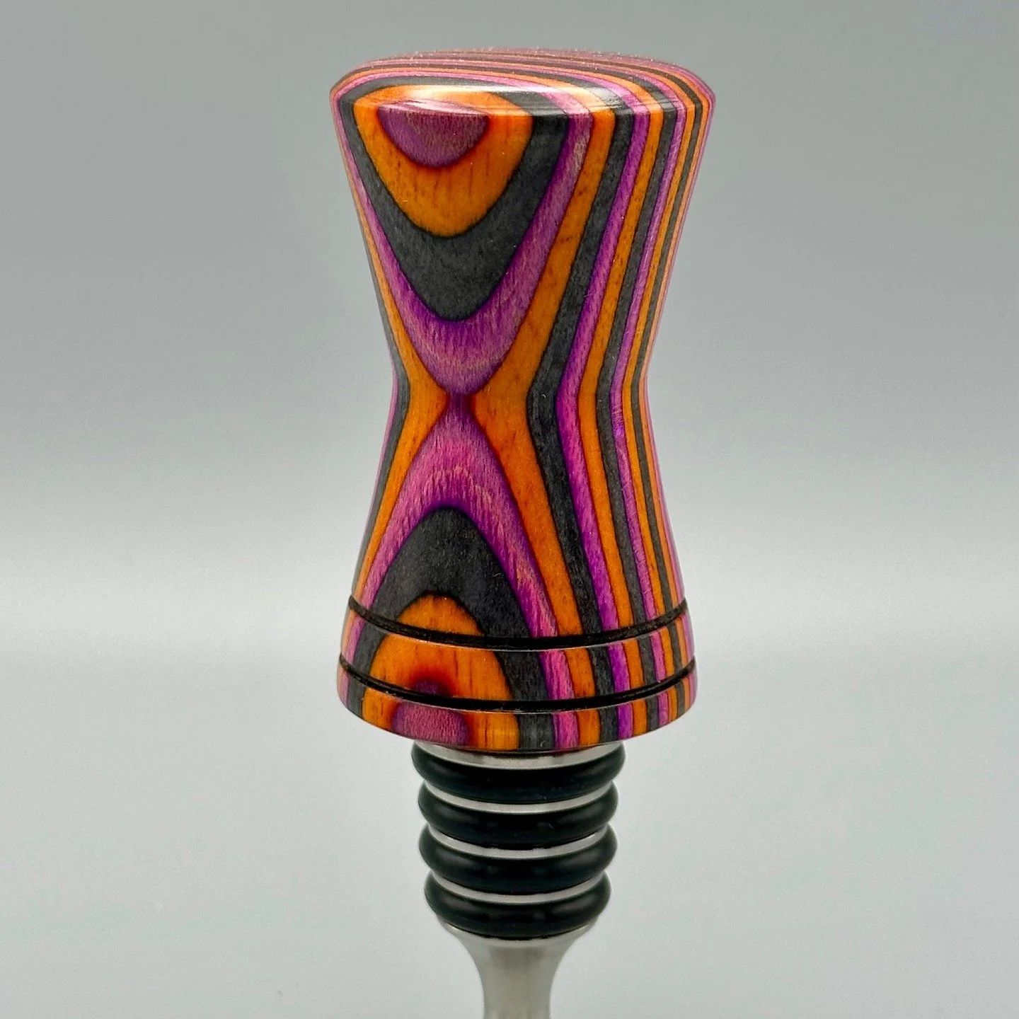 Artist: Jeff Schoolcraft
Instagram: jaschoolcraft
Web: https://creativeturnsllc.com/
Macaw Spectraply Stainless Steel Bottle Stopper
Hand turned wooden, stainless steel bottle stopper. The top is made from orange, pink and charcoal layered spectra pl