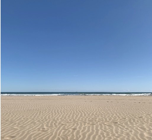 Handstand Fiesta Valencia sandy beach with ocean waves under a clear blue sky.