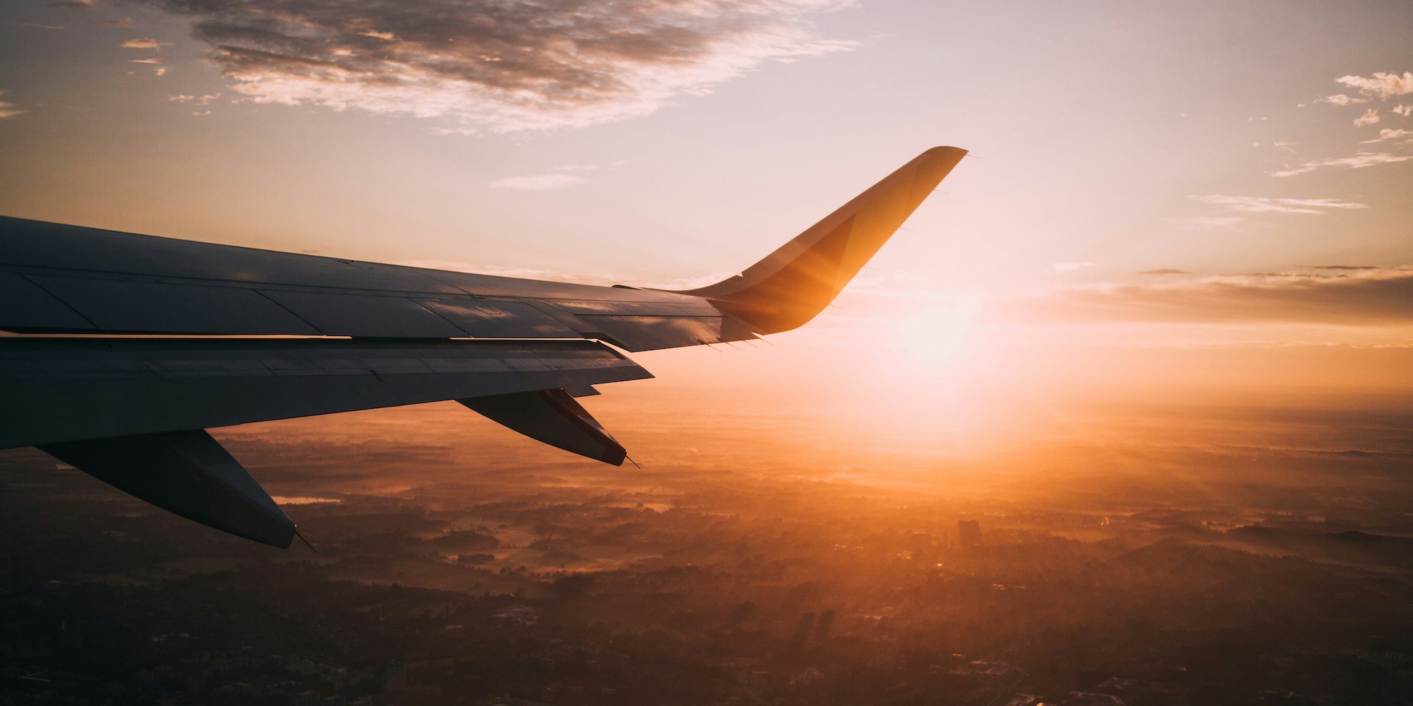 travel guide - plane wing with sun behind