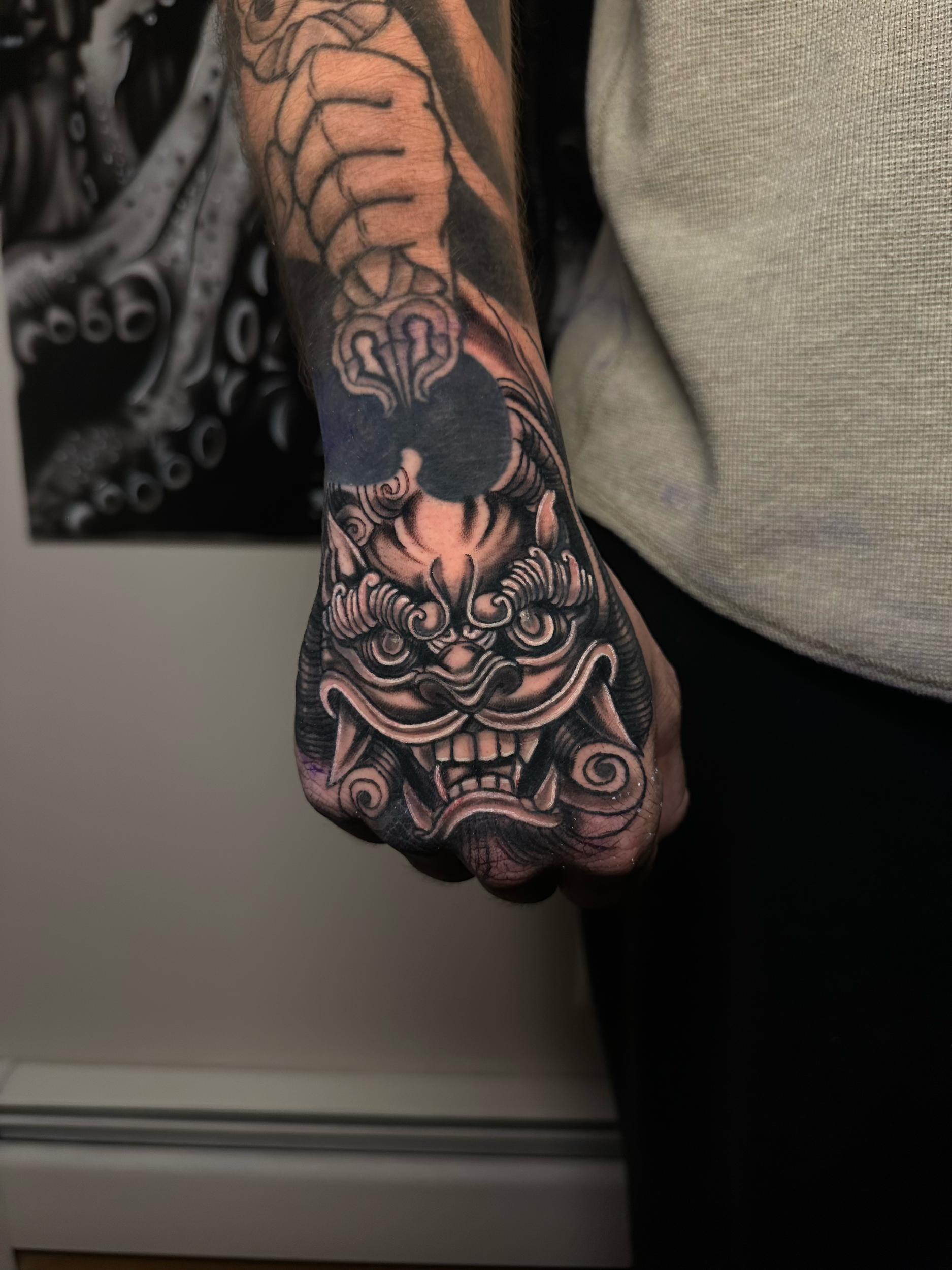 Close-up of a hand tattoo featuring an intricate and fantastical creature design with detailed shading.
