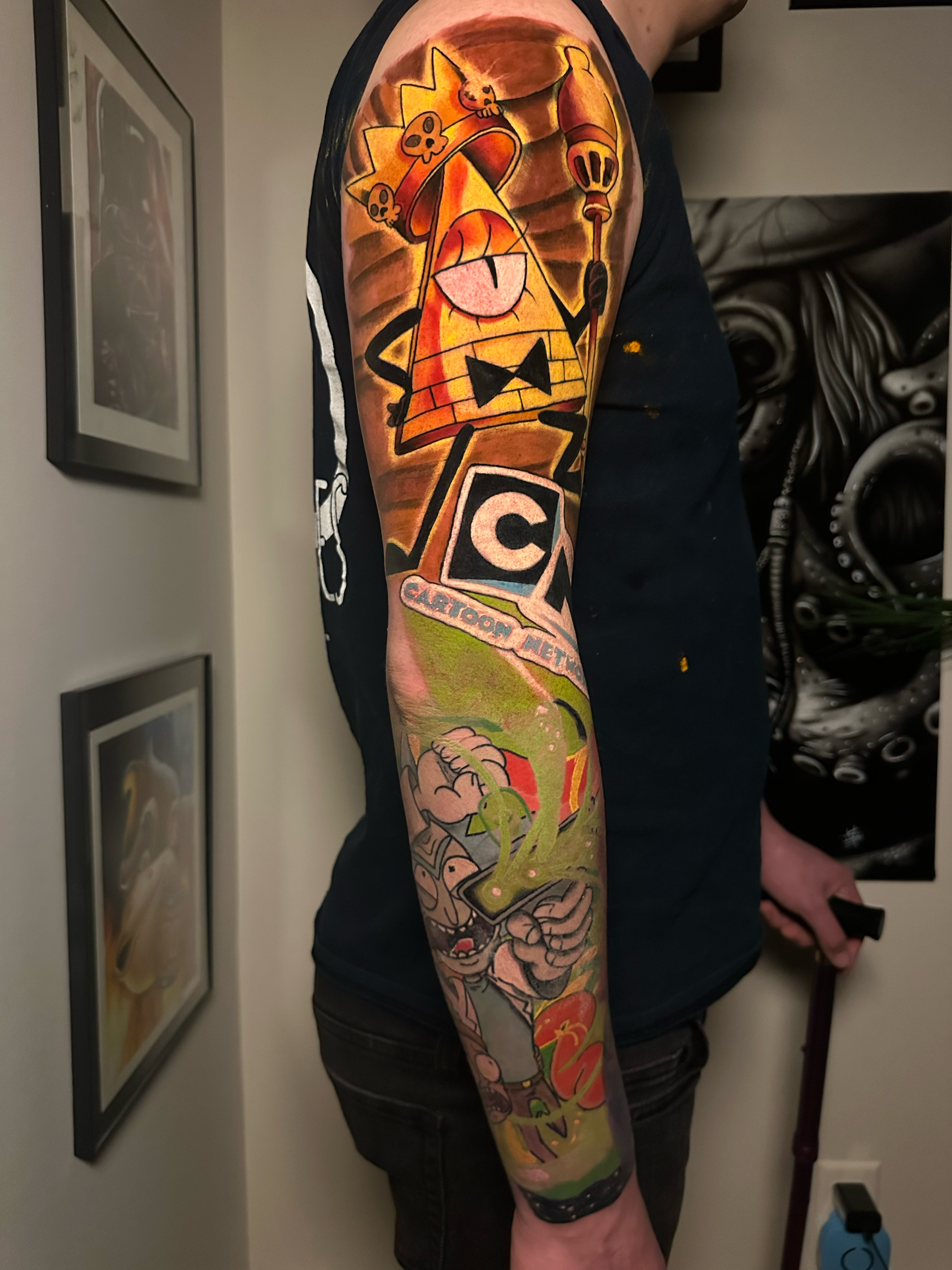Colorful cartoon-themed tattoo sleeve on a person's arm, featuring various characters and abstract designs.