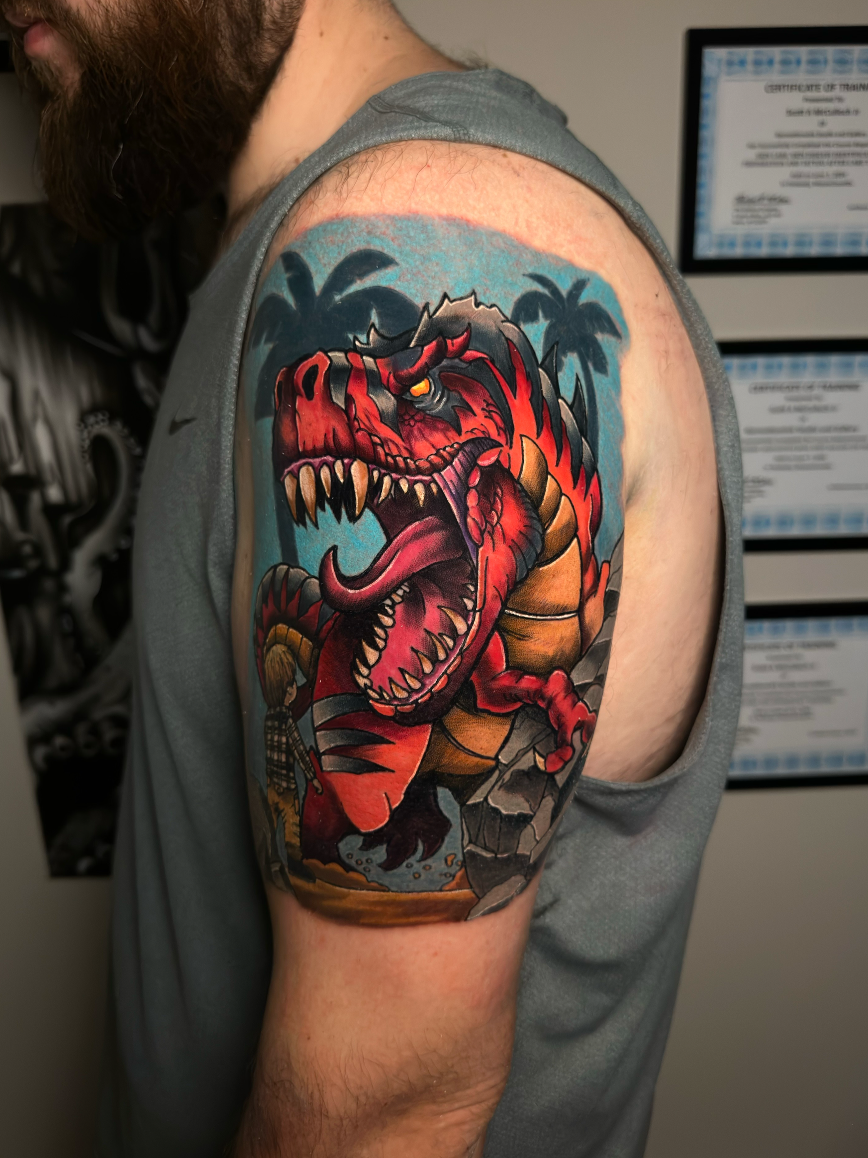Colorful dinosaur tattoo on upper arm, with sharp teeth and detailed designs.