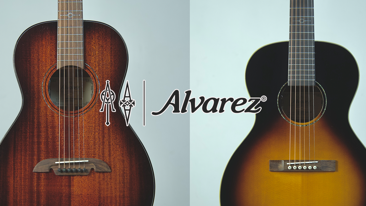 A small acoustic guitar lying on wooden floor next to sheet music.