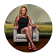 Person sitting on bench outdoors with green grass background, wearing a black dress and red shoes.