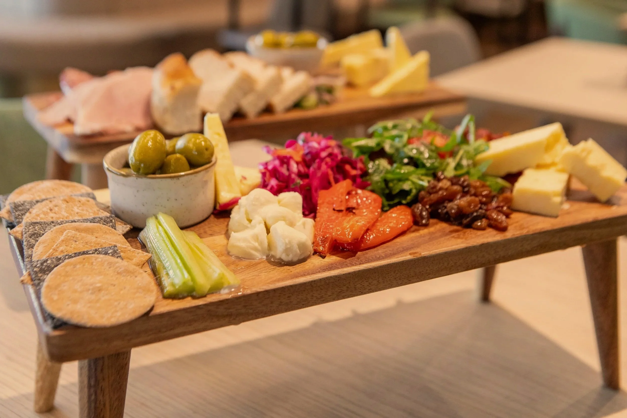 Charcuterie board with green olives, celery sticks, cheese, pickled vegetables, crackers, and assorted meats and vegetables.
