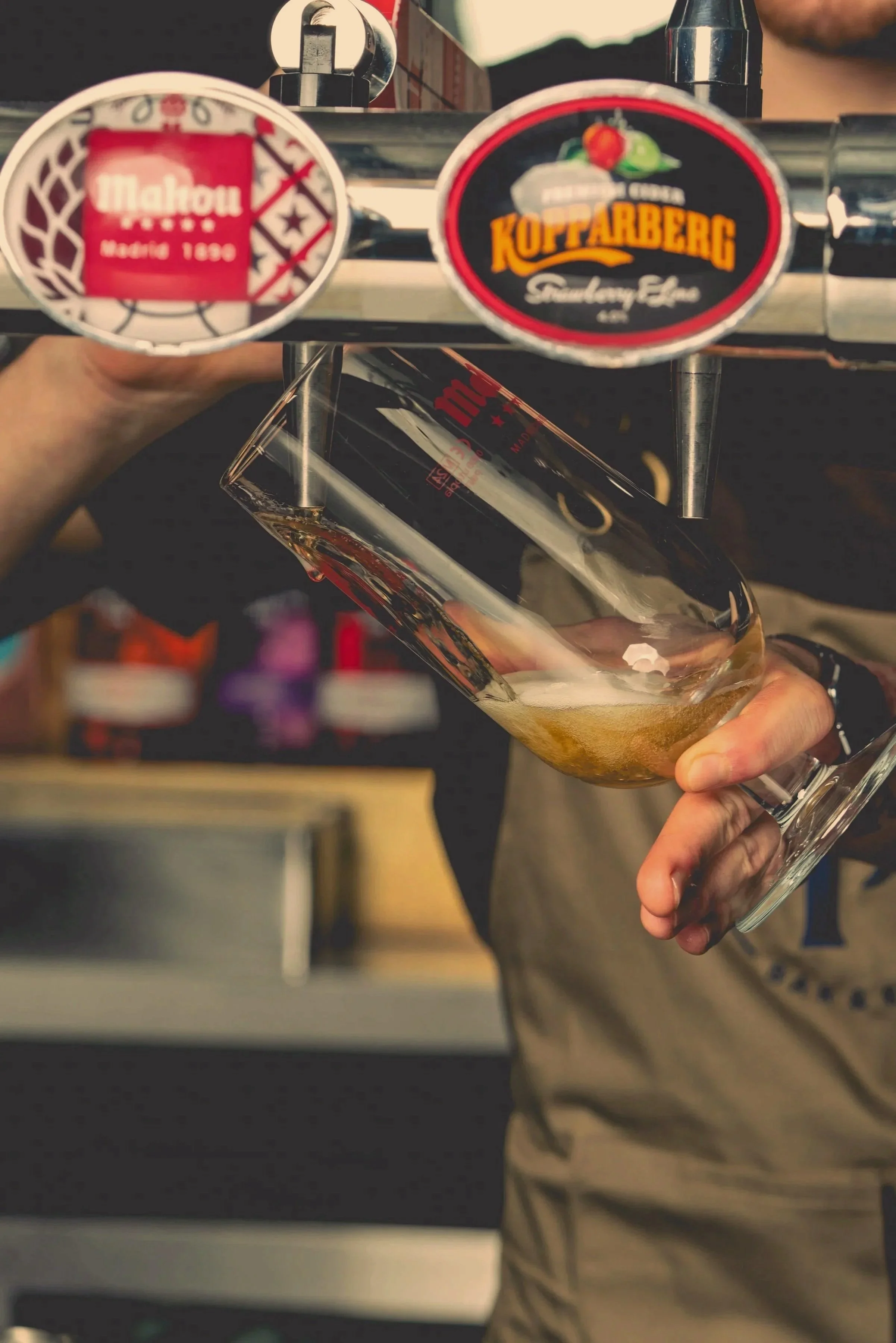 A person pouring beer from a tap into a glass.