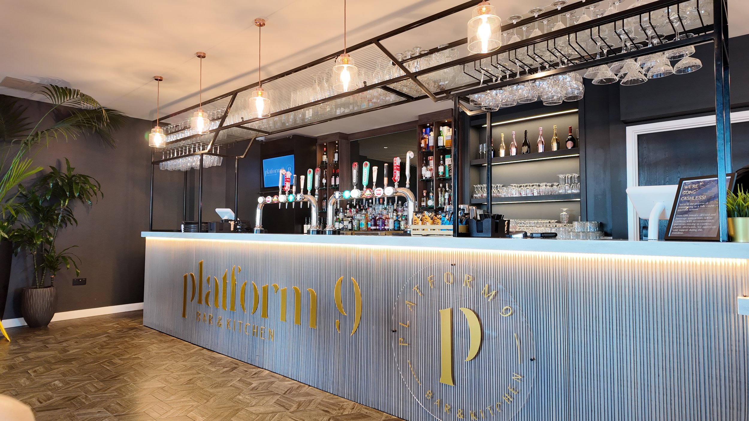 Modern bar counter with beer taps, glassware shelves, and alcohol bottles, inside a stylish restaurant called Platform Bar & Kitchen.