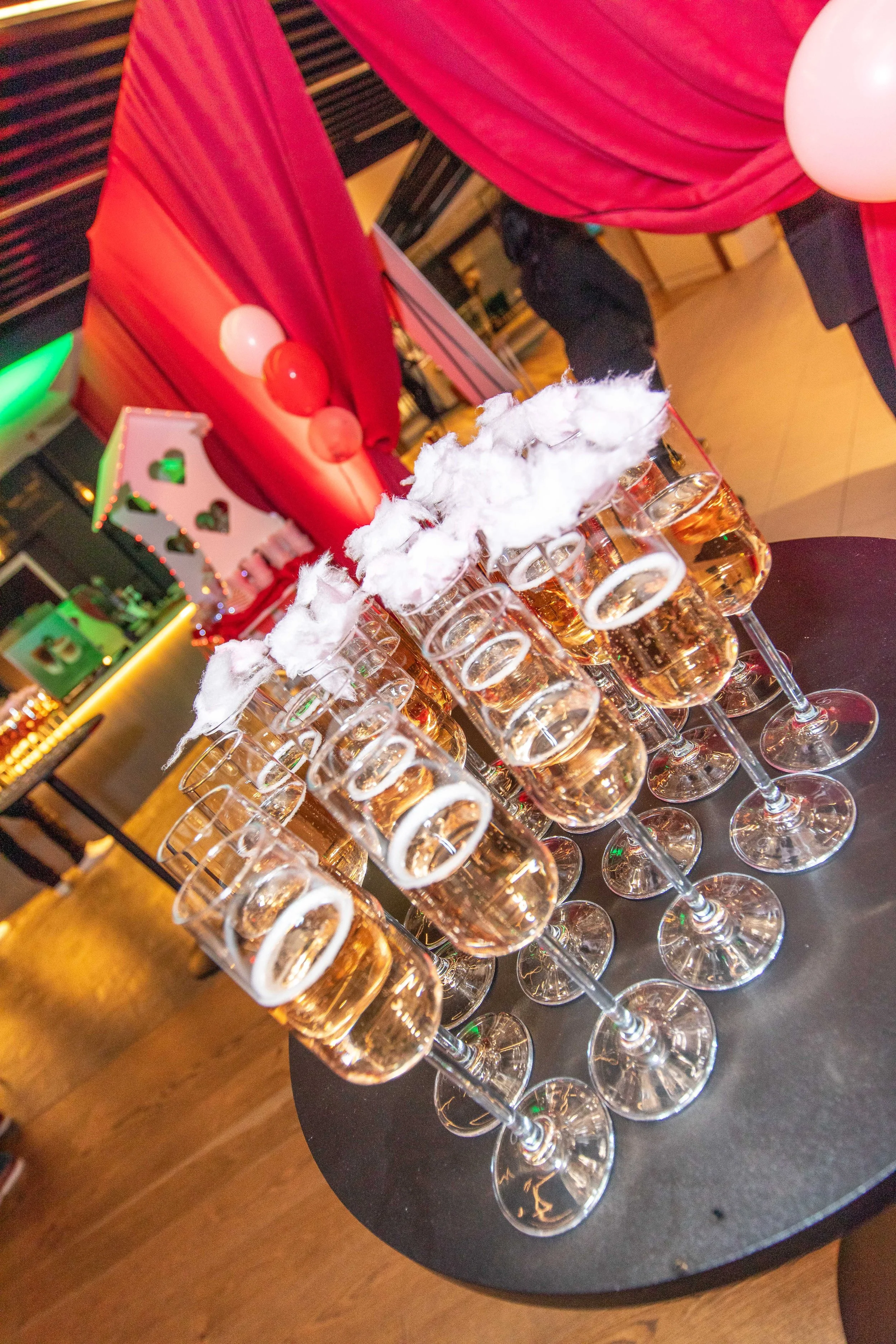 Several champagne glasses with cotton decorations on top, arranged on a table at a celebration or event.