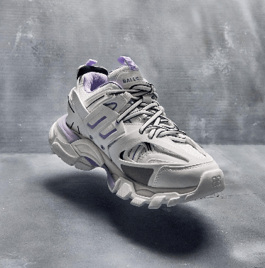 A pair of gray and purple Balenciaga sneakers on a gray surface.