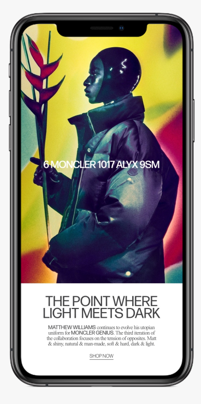 An advertisement on a smartphone screen features a person wearing a black helmet and a shiny black jacket, holding a long, dark red flower. The background has bright, vibrant colors blending into each other. The text on the screen promotes a collaboration between Moncler and Alyx.