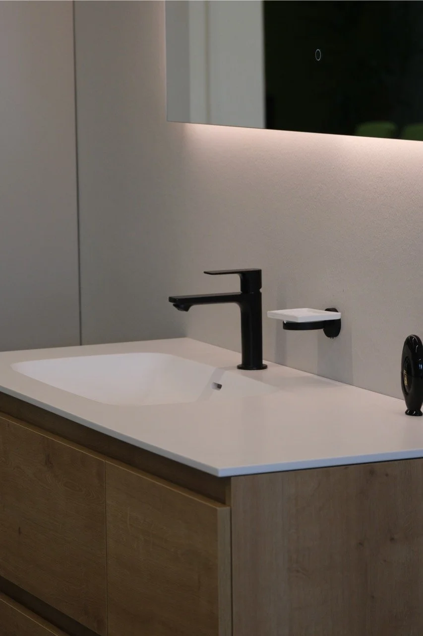 Waschbecken mit schwarzem Wasserhahn und Spiegel in modernem Badezimmer.