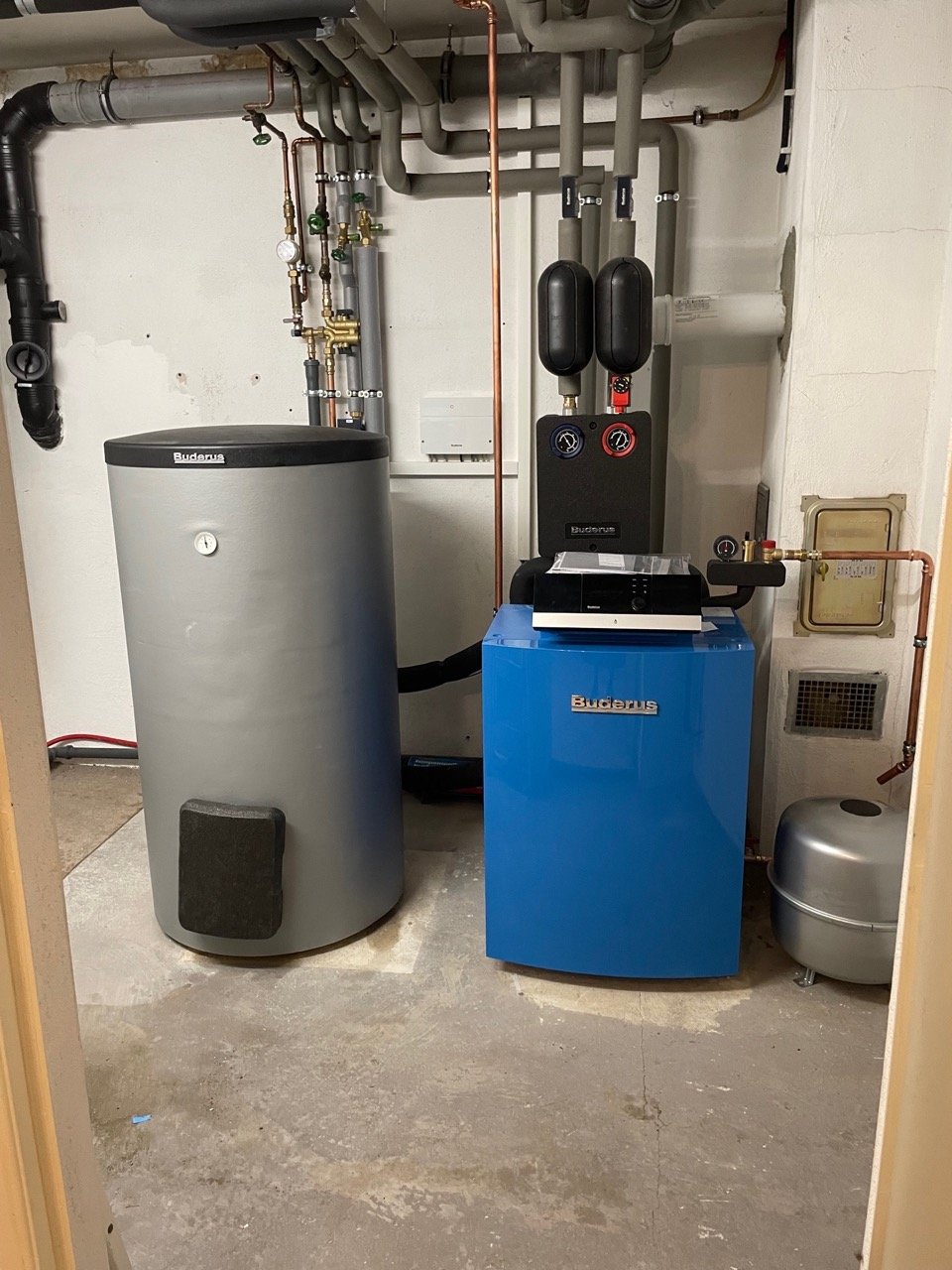 Heizungsanlage mit Wasserspeicher, Heizungsregler und Zirkulationspumpe in einem Technikraum.