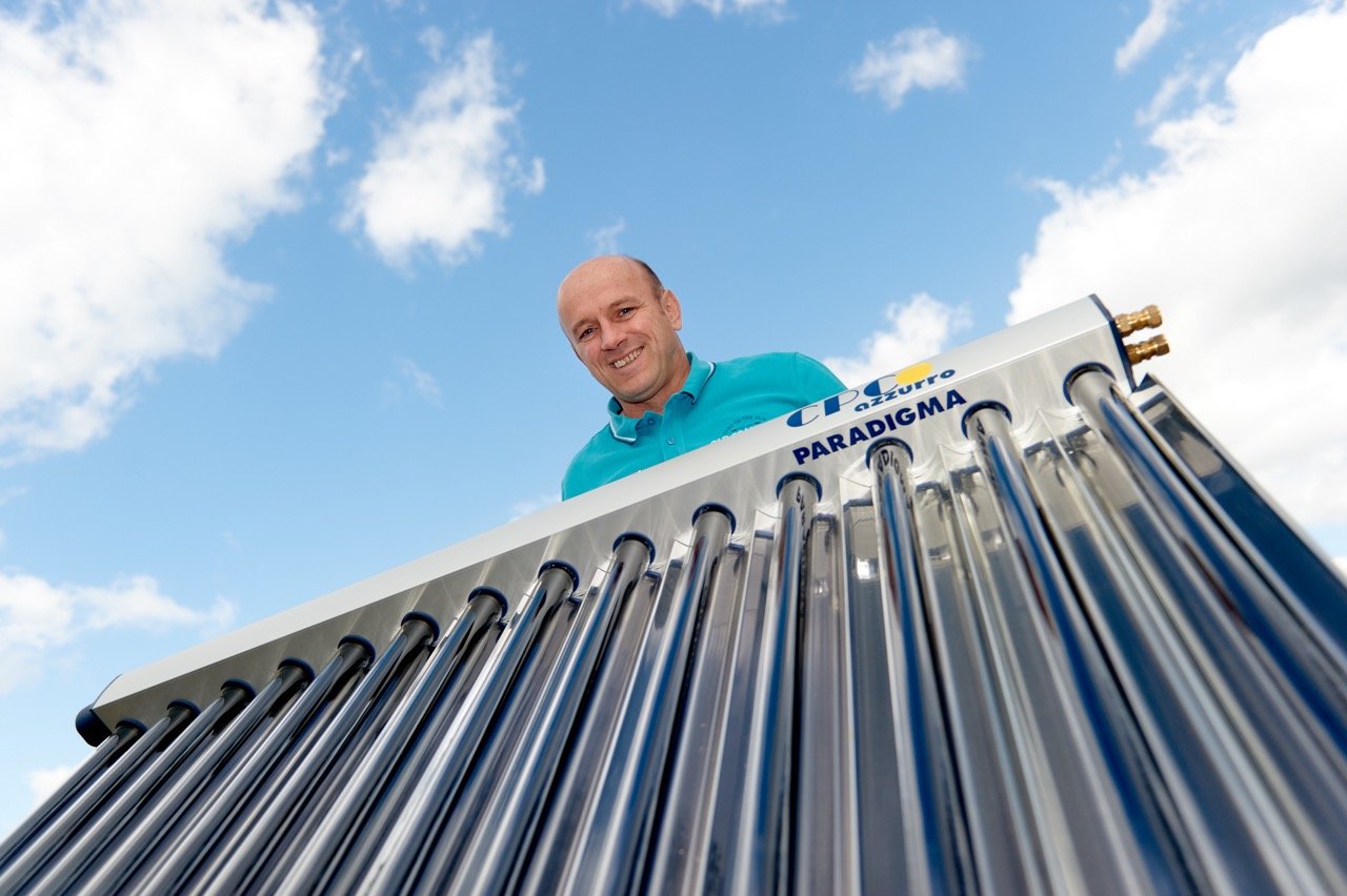 Mann steht vor einer Sonnenkollektor-Kooperation gegen den Himmel.