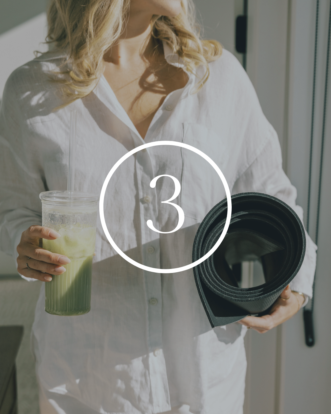 Woman holding a glass of green smoothie and a rolled yoga mat.