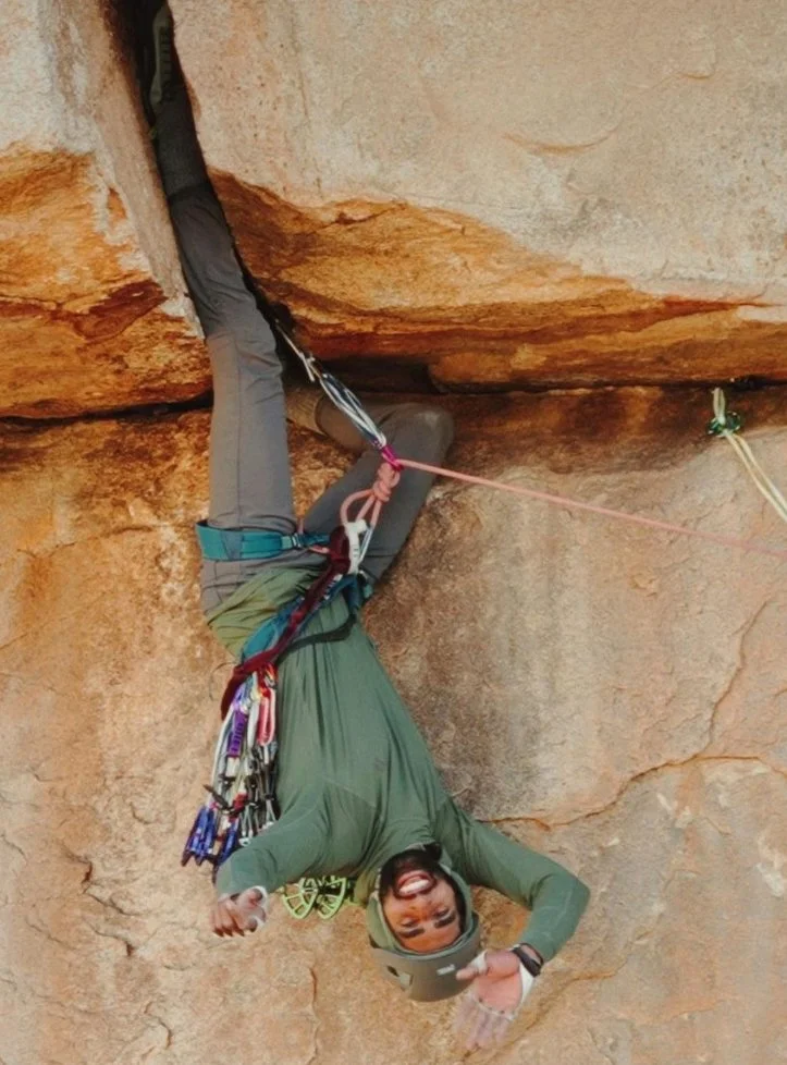 A rock climber in climbing gear hanging upside down in an offwidth crack, Indian Creek Climbing Area, Monticello, Utah.